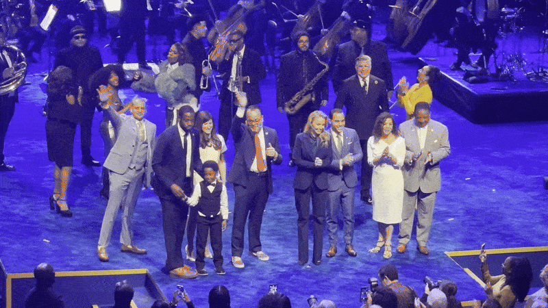 Mayor Helena Moreno and City Council members wave on stage. Musicians stand behind them.