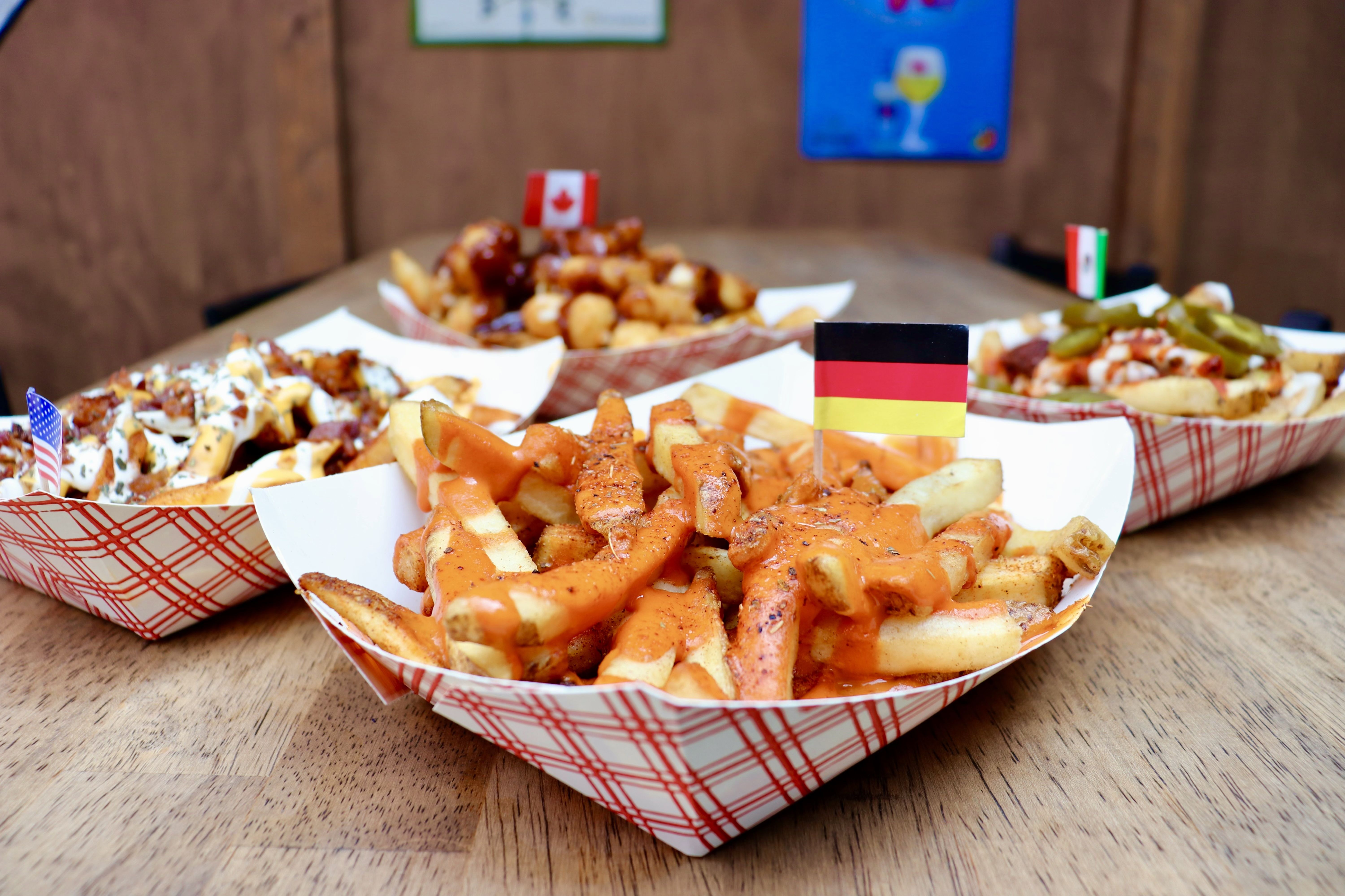 Paper baskets with french fries and covered in sauce.