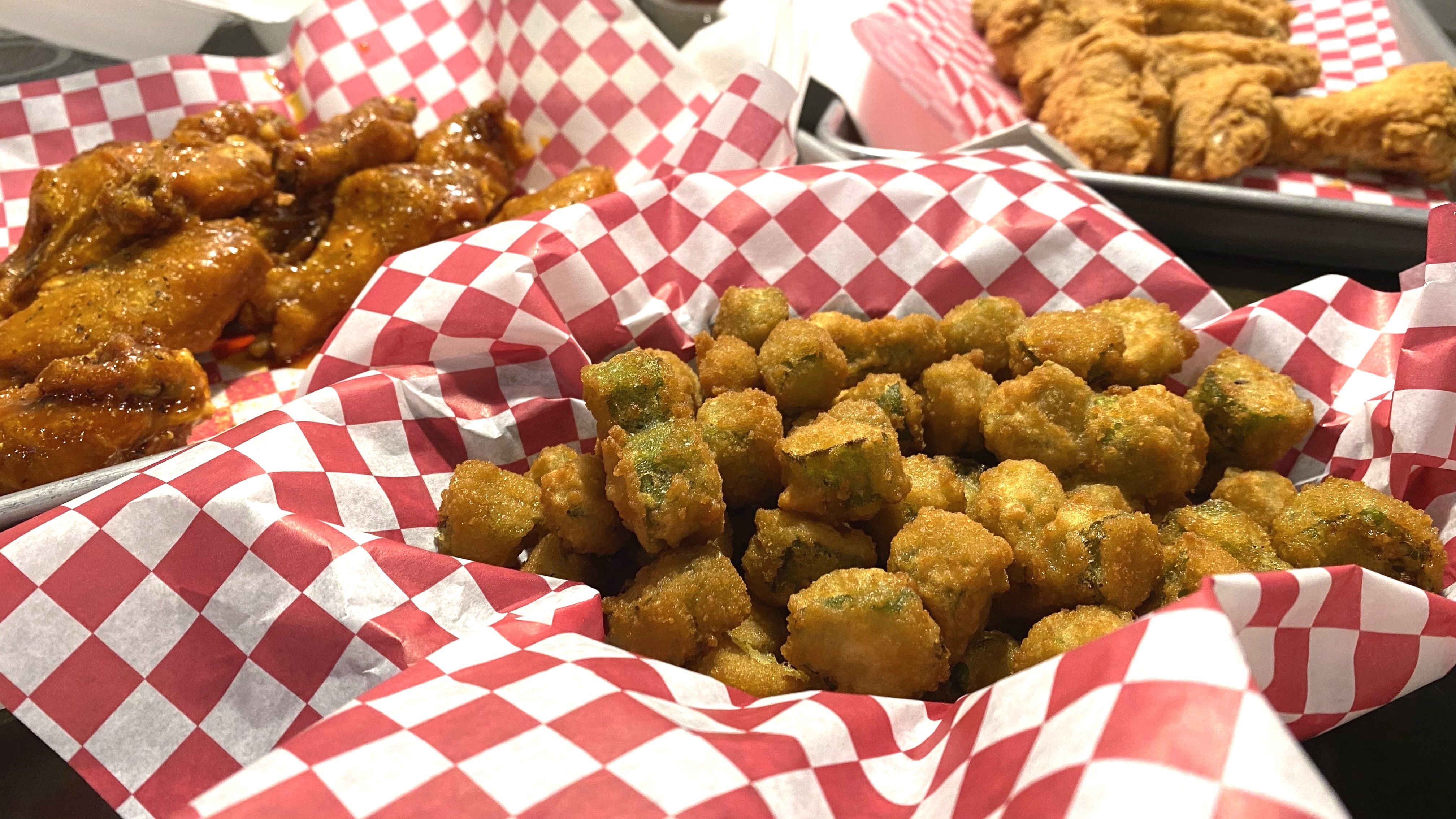A photo of fried okra and wings on paper-covered platters.