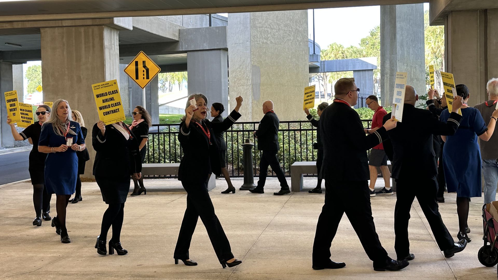 25 uniformed flight attendants march in a circle with signs reading "world class airline, world class contract."
