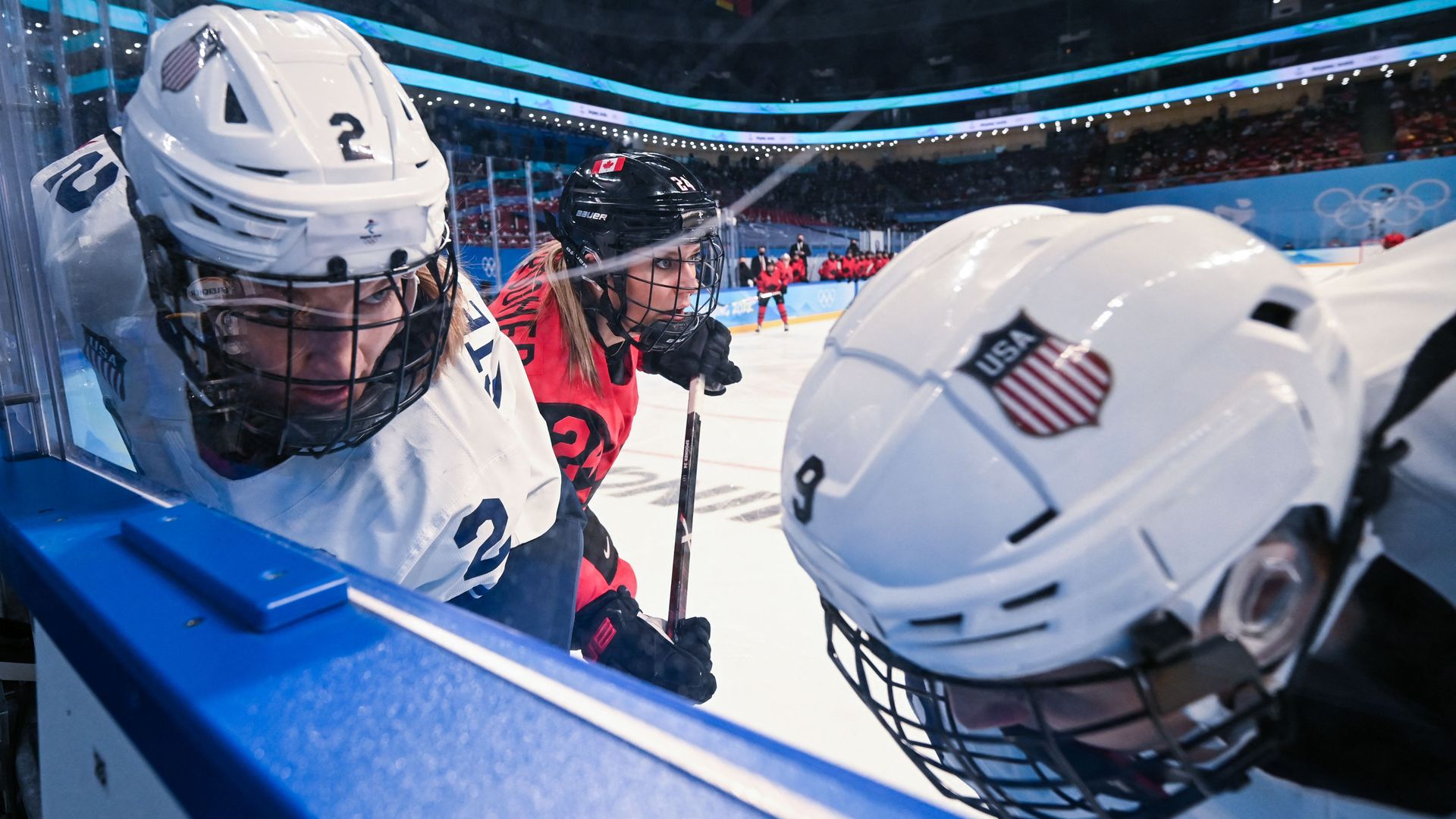 Close-up image of U.S. women's hockey players scrambling for the puck against the boards 