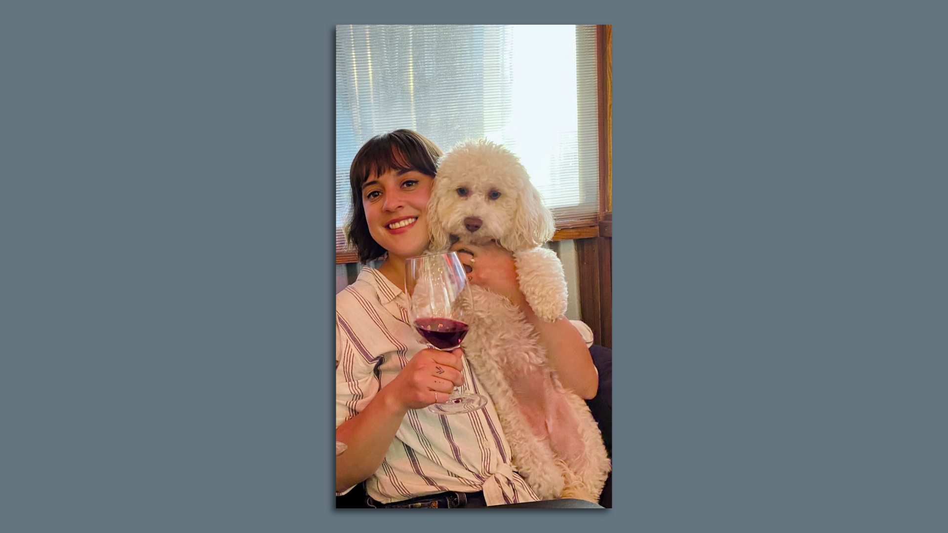 A woman holding a dog and a glass wine