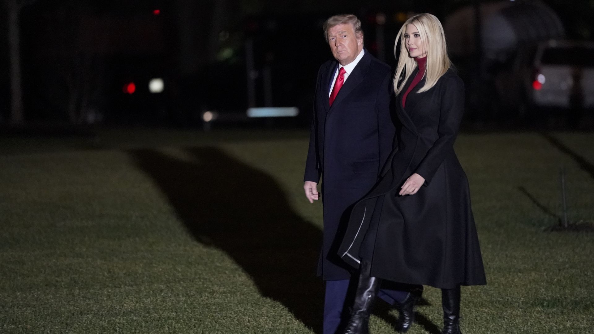 Ivanka Trump walks with her father, Donald Trump, over a lawn at night.