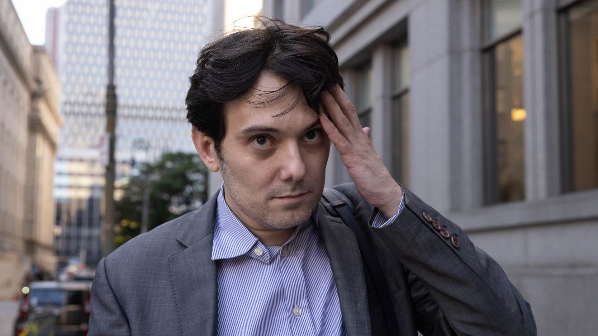 Martin Shkreli walks down a street, brushing back his hair.