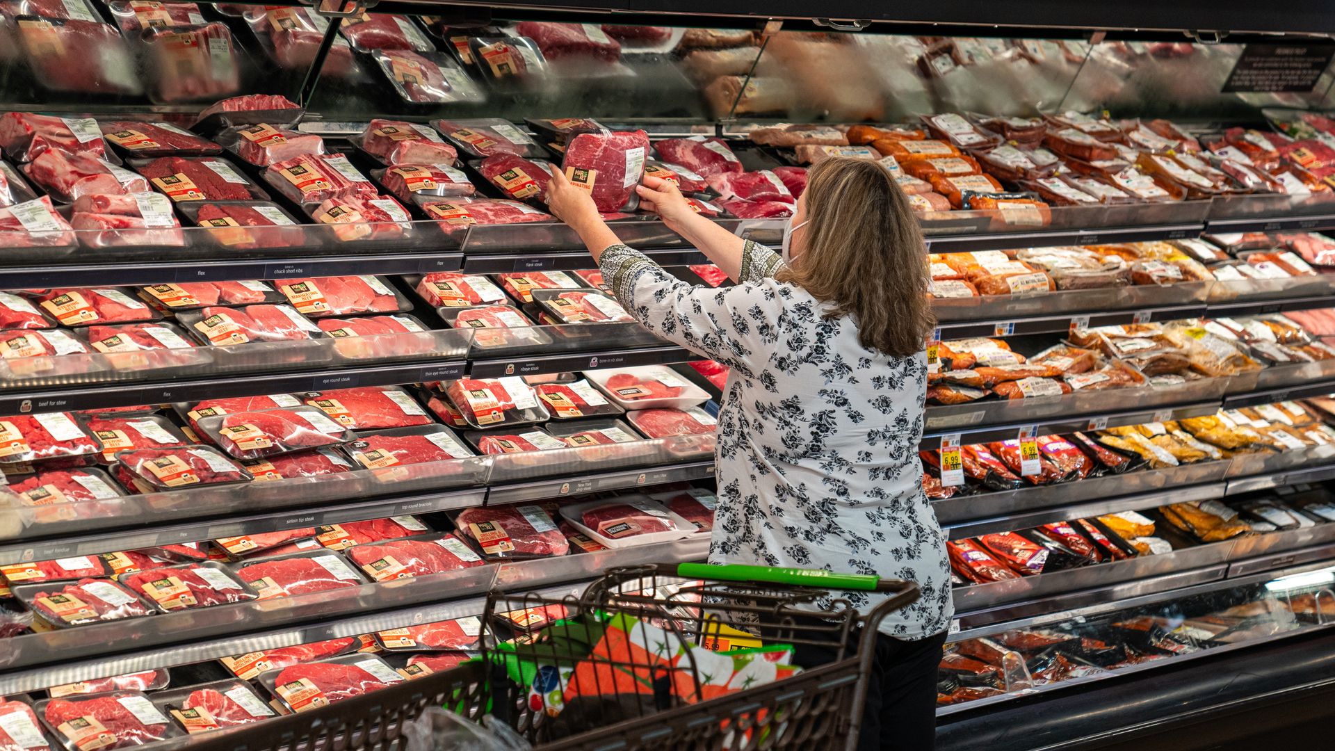 Shopper looks at meat at grocery store