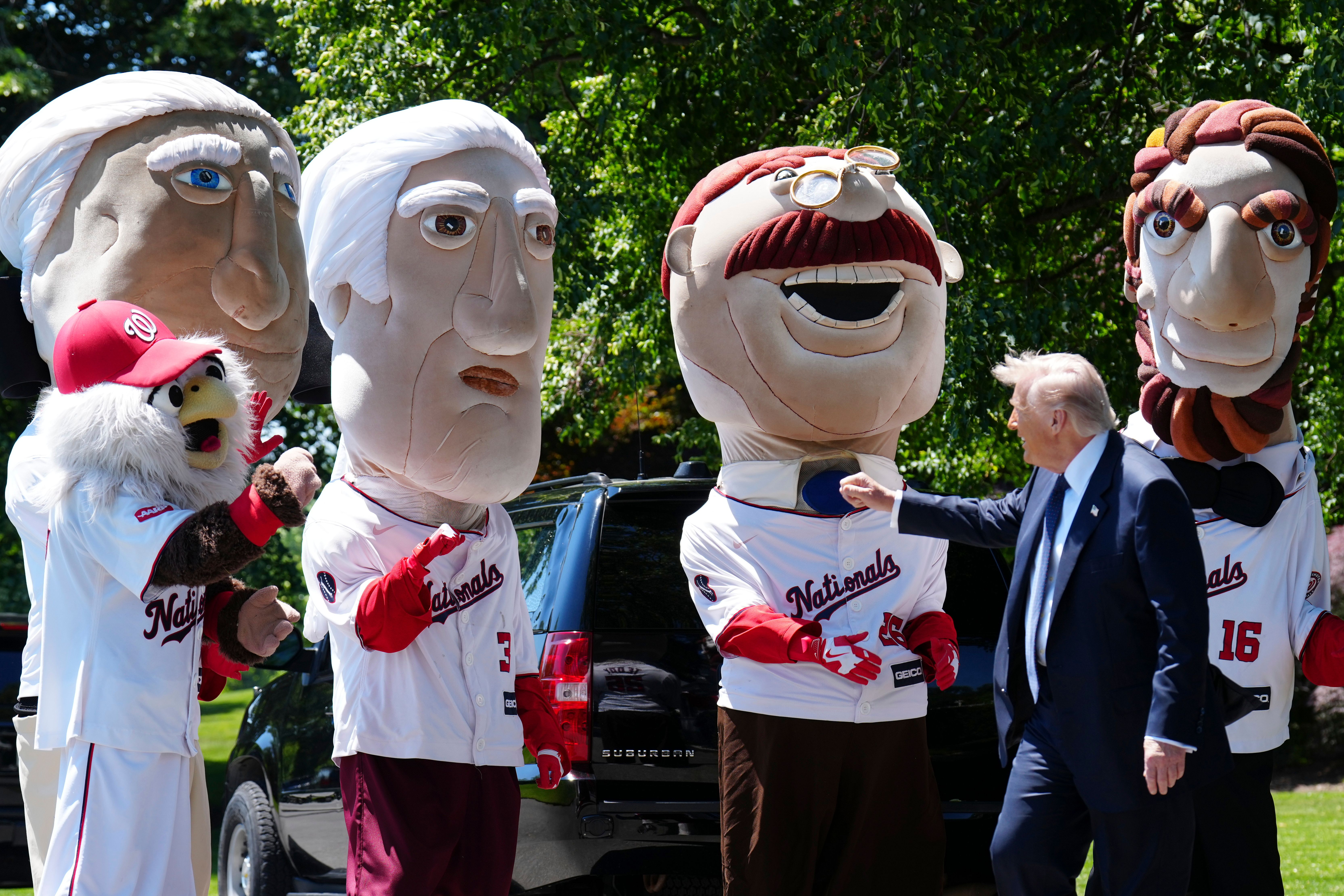 President Trump greets the mascots from the Washington Nationals' presidents race — George Washington, Thomas Jefferson, Teddy Roosevelt and Abraham Lincoln — on the South Lawn of the White House.