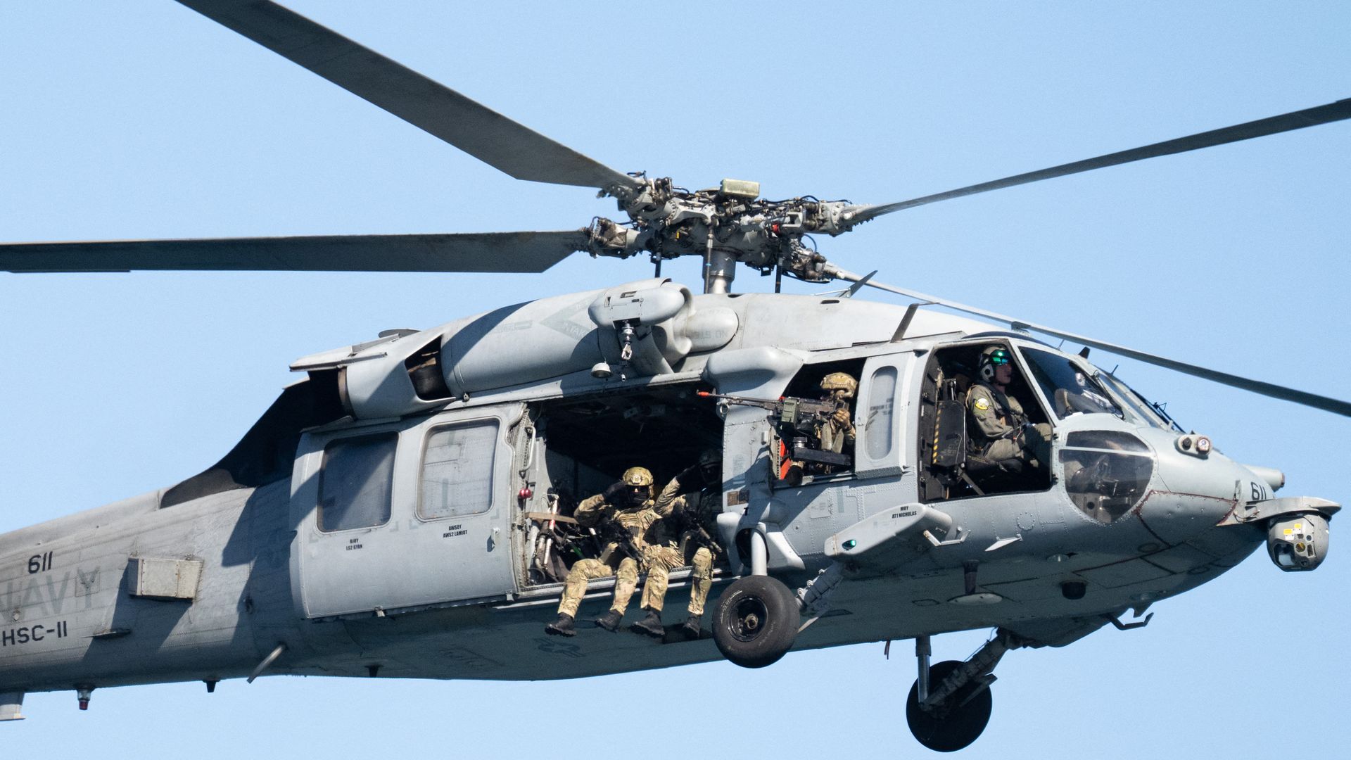 Image shows military members on a helicopter. 