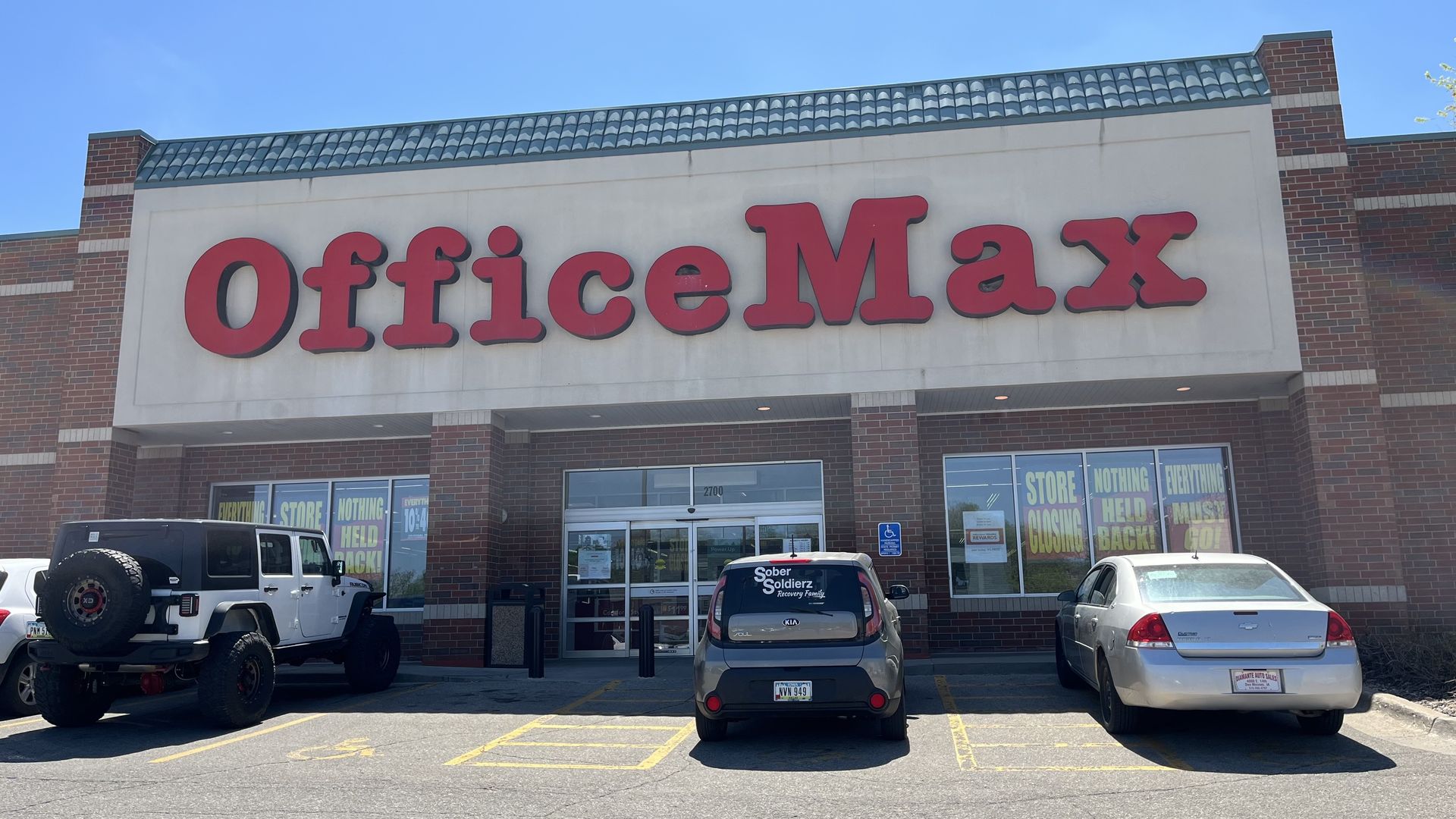 The front of office max with signs in the window about closing