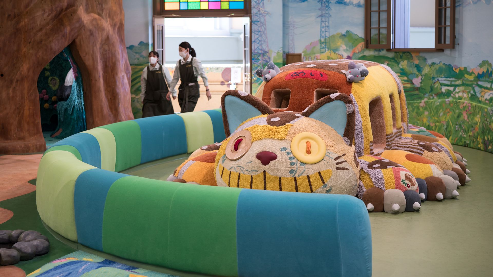 two women walk past a life-sized Cat Bus, from the film 'My Neighbor Totoro' in Japan