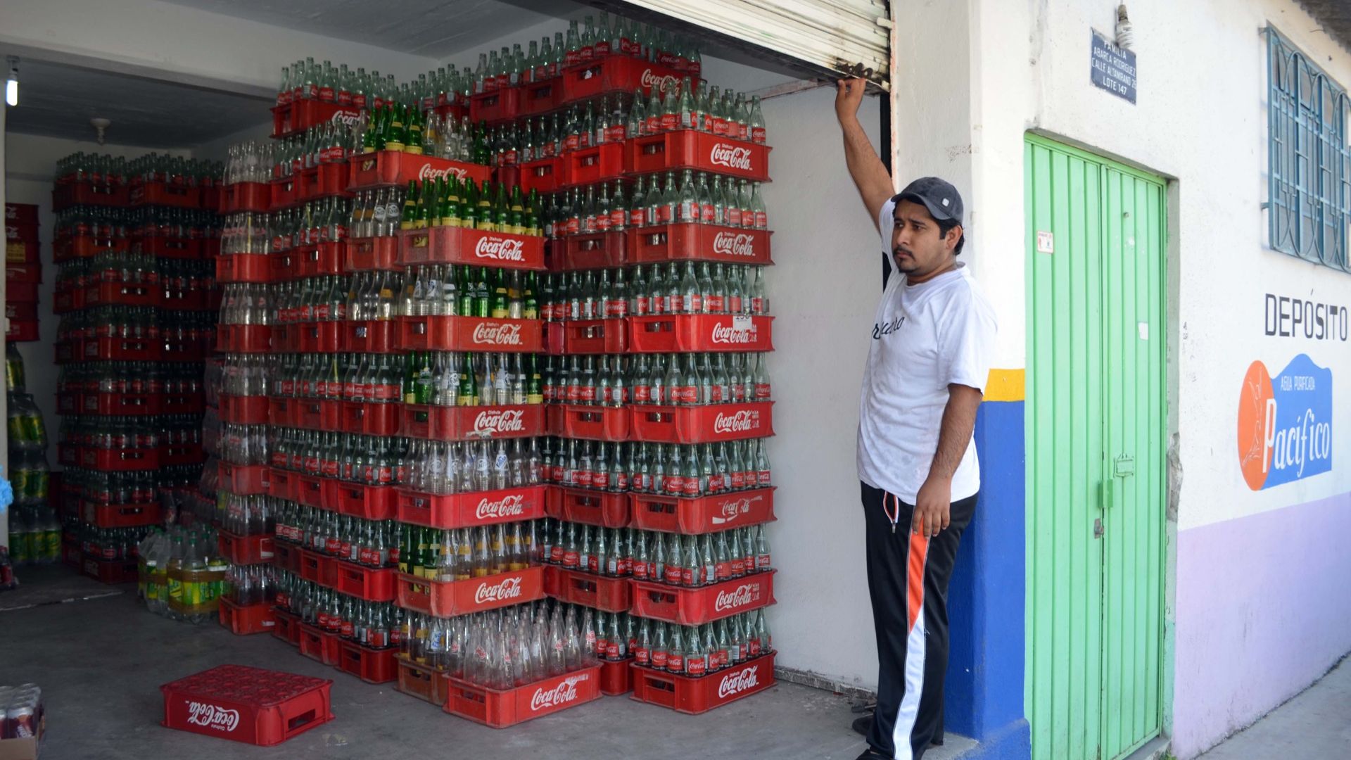 An man at a beverage deposit with cases of mostly empty Coke bottles in Mexico