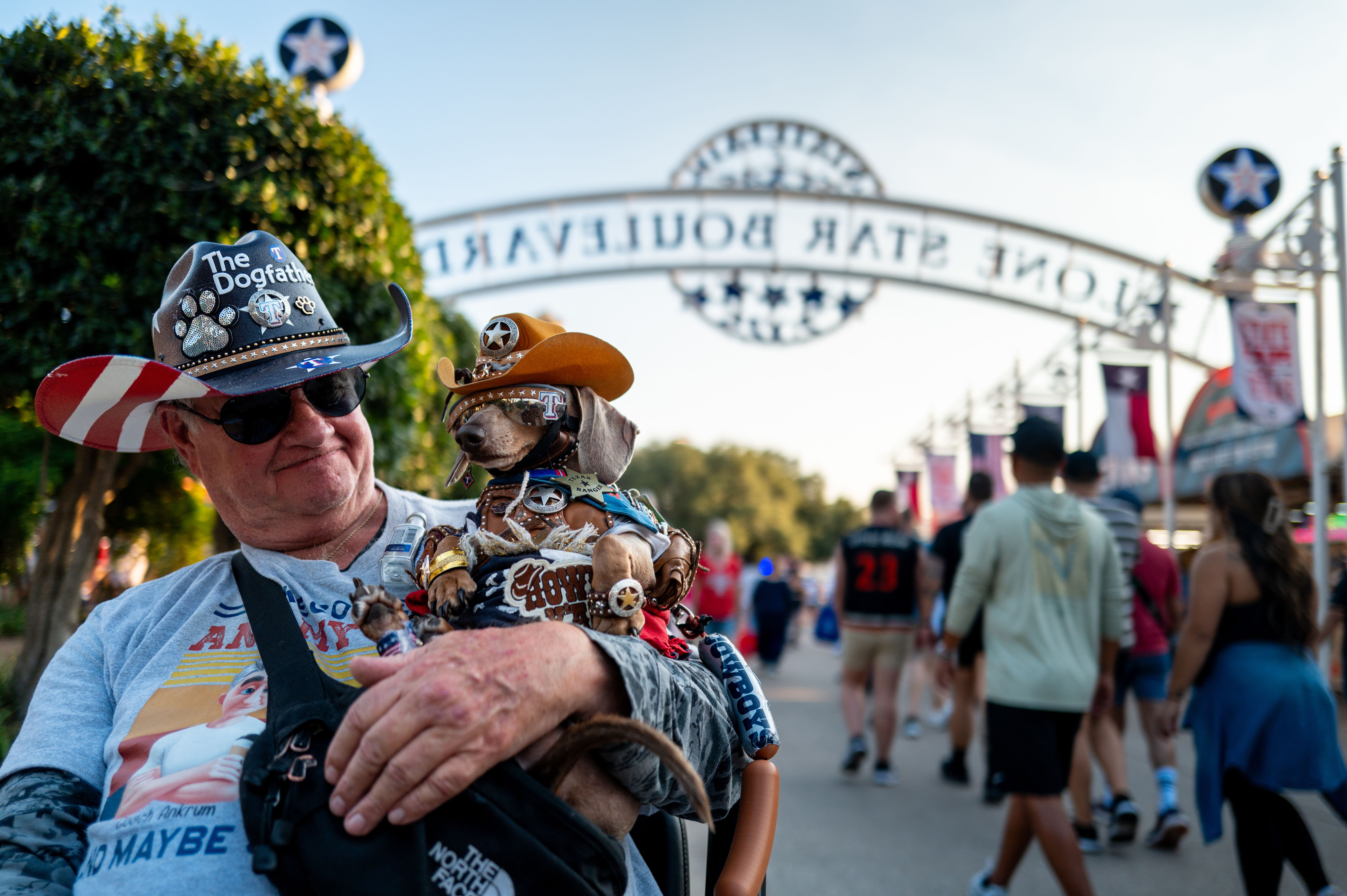 A man holds his dog, Buttercup, while wearing an outfit around the theme of "The Dogfather." 