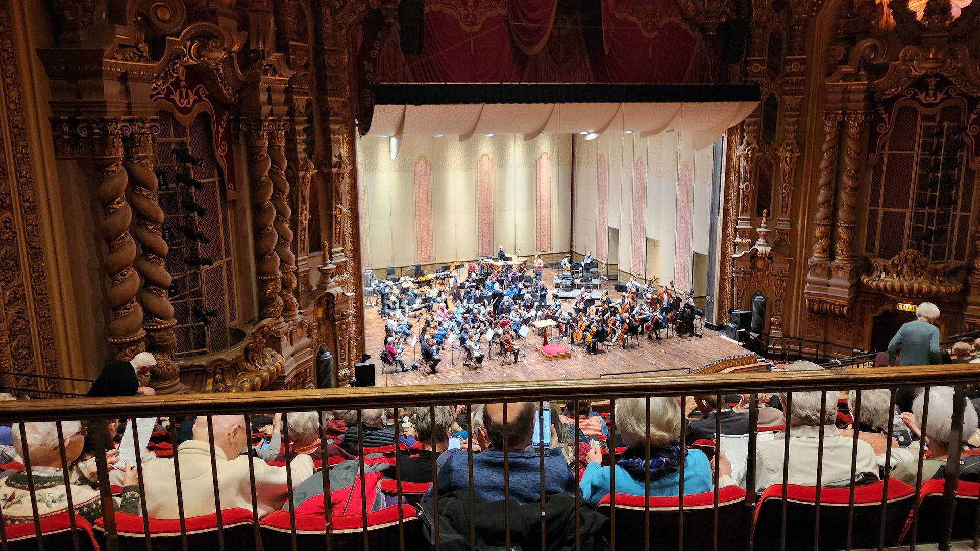 A balcony view of an orchestra rehearsal, with players on stage.