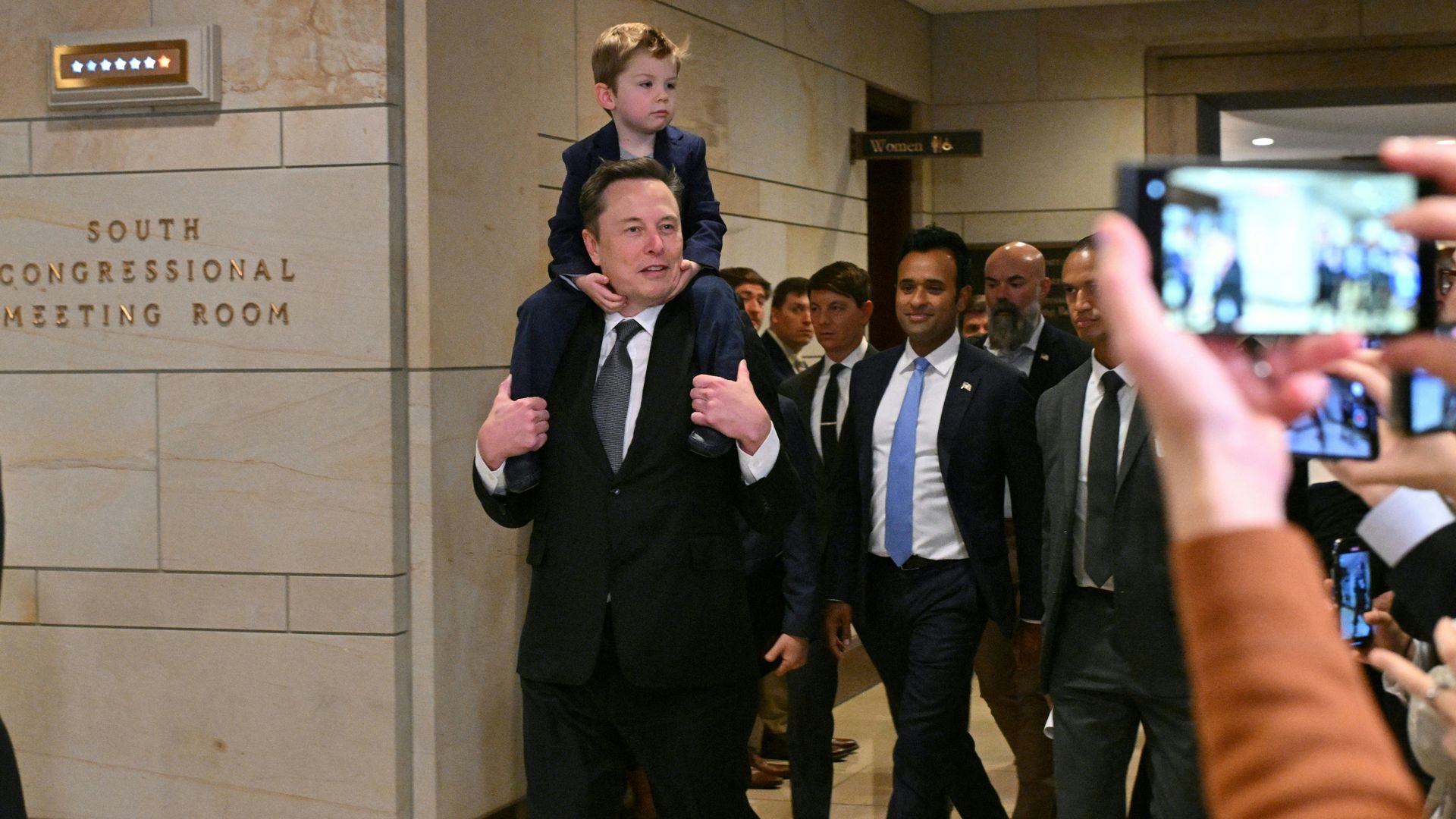 Tesla CEO Elon Musk with his son on his shoulders and Businessman Vivek Ramaswamy (C) arrive at the US Capitol on December 5, 2024 in Washington, DC. 