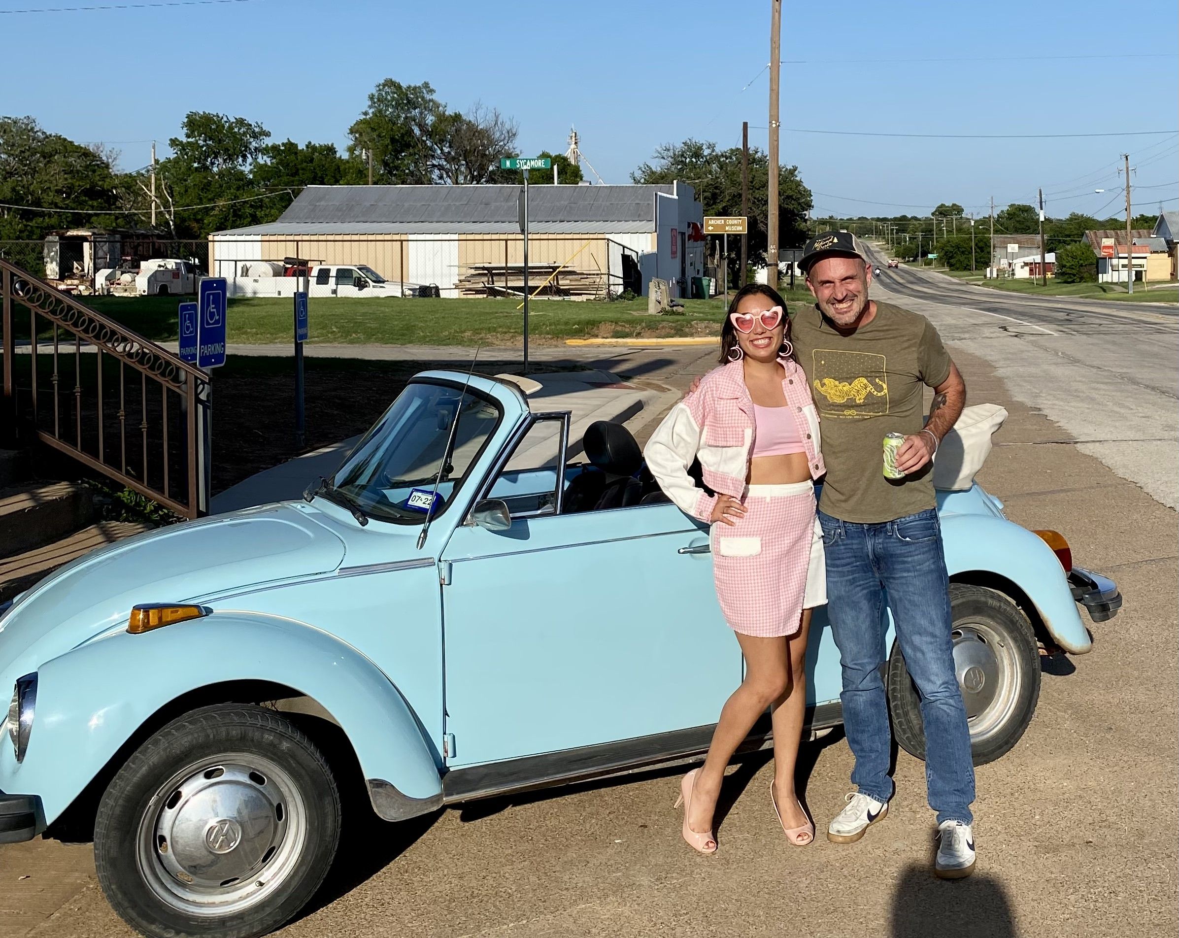 Ben and Selene pose in front of a blue old VW bug