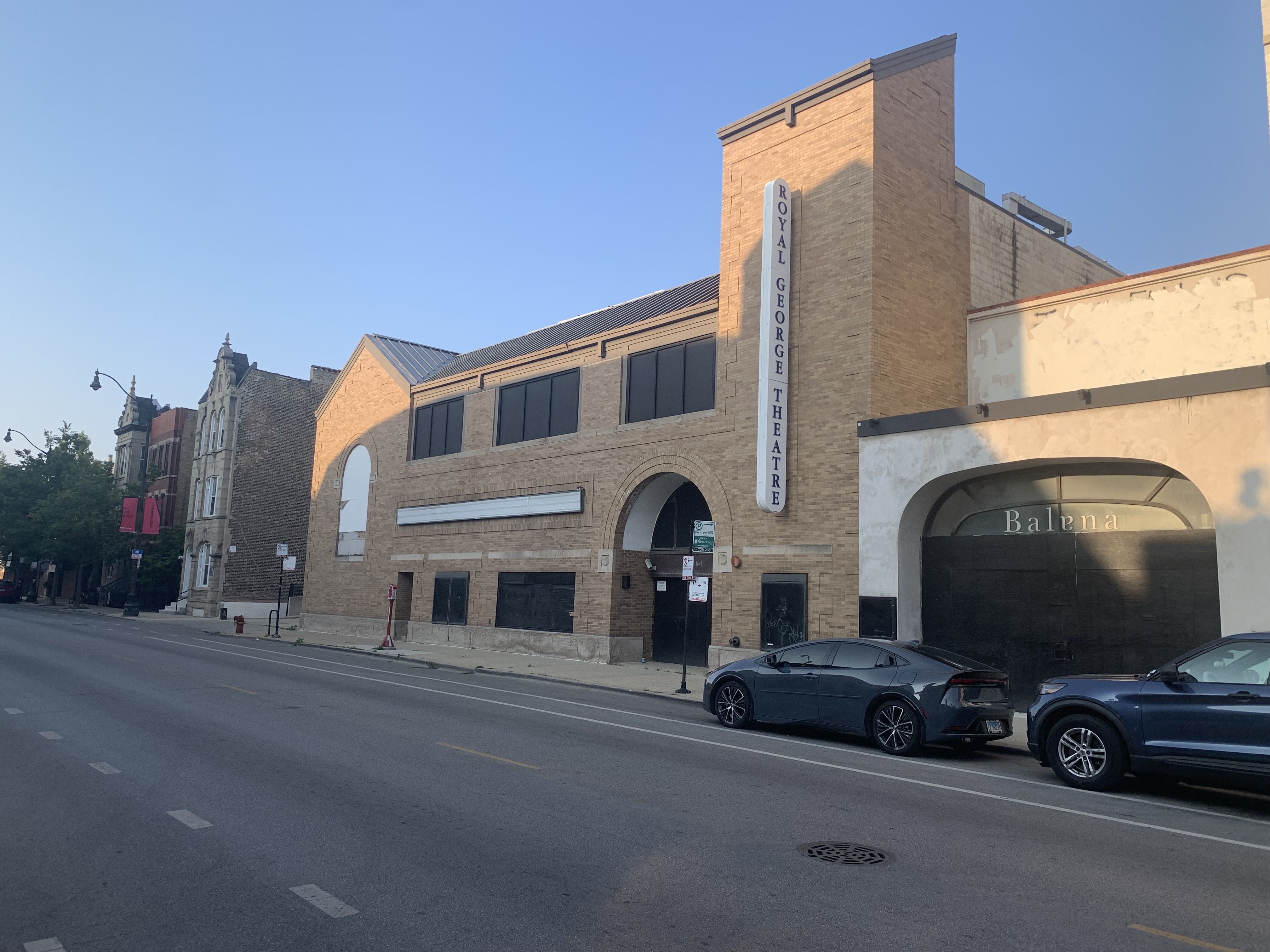 Photo of a building on a street with cars parked in front of it. 