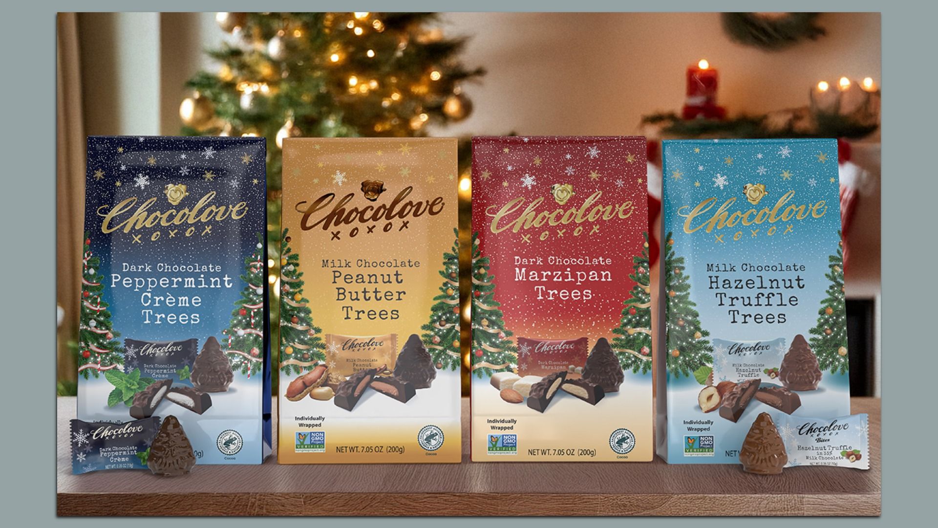Four Chocolove chocolate boxes in blue, gold, red, and light blue with festive trees, labeled Peppermint Crème, Peanut Butter, Marzipan, and Hazelnut Truffle, next to a Christmas tree.