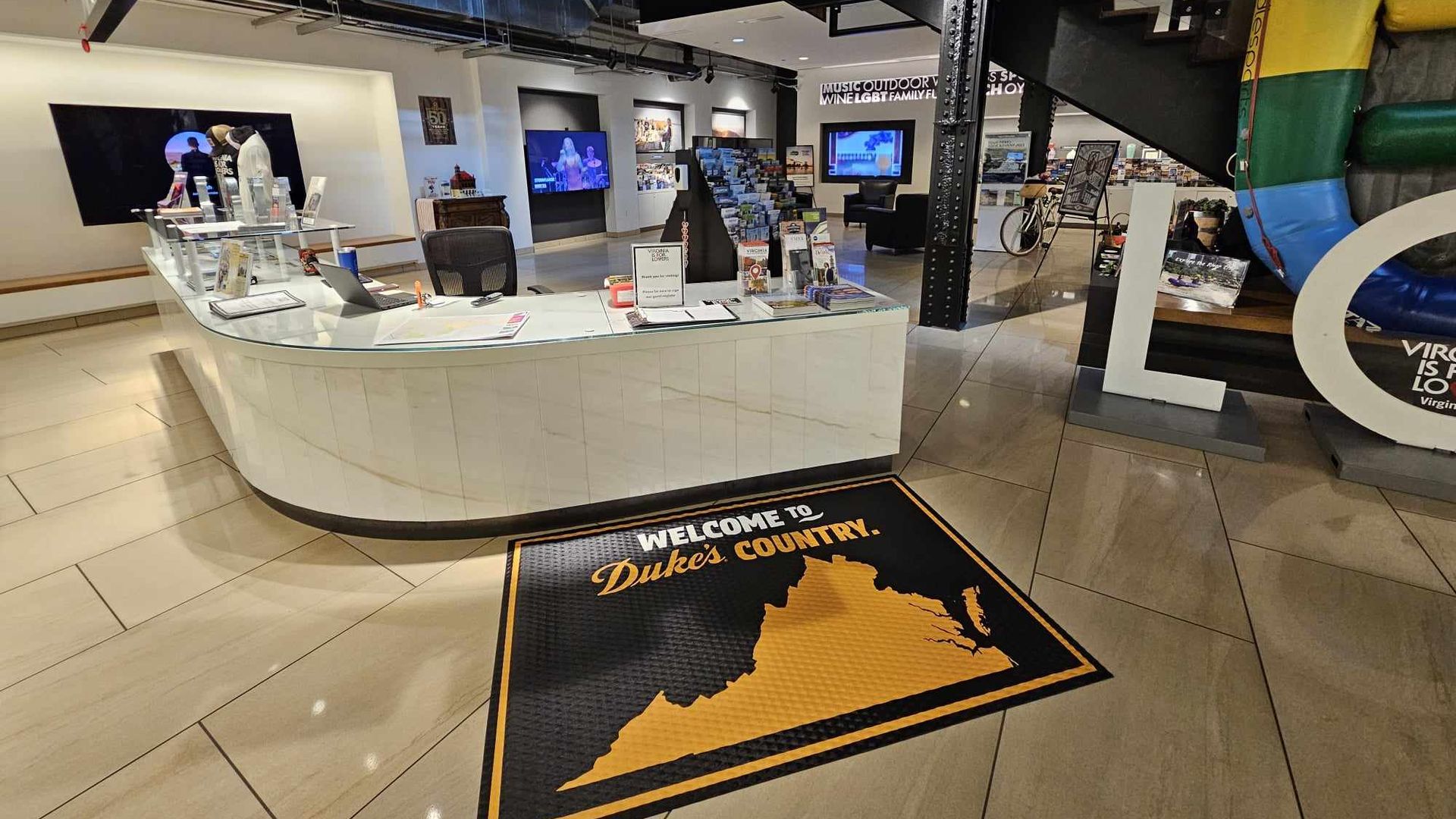 The inside of a vistors center with a welcome to Duke's country mat 