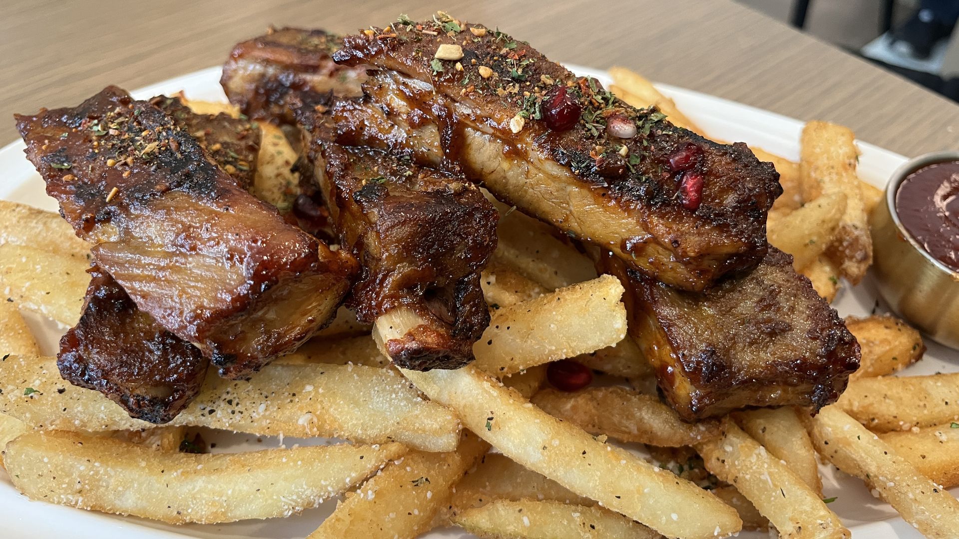 Five ribs stacked on top of a plate of french fries 