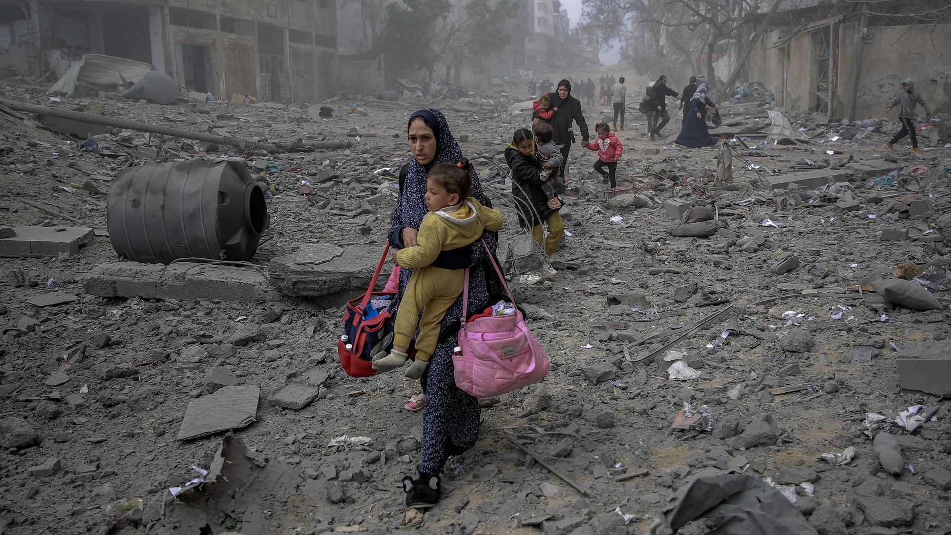 Woman holding child amid ruins