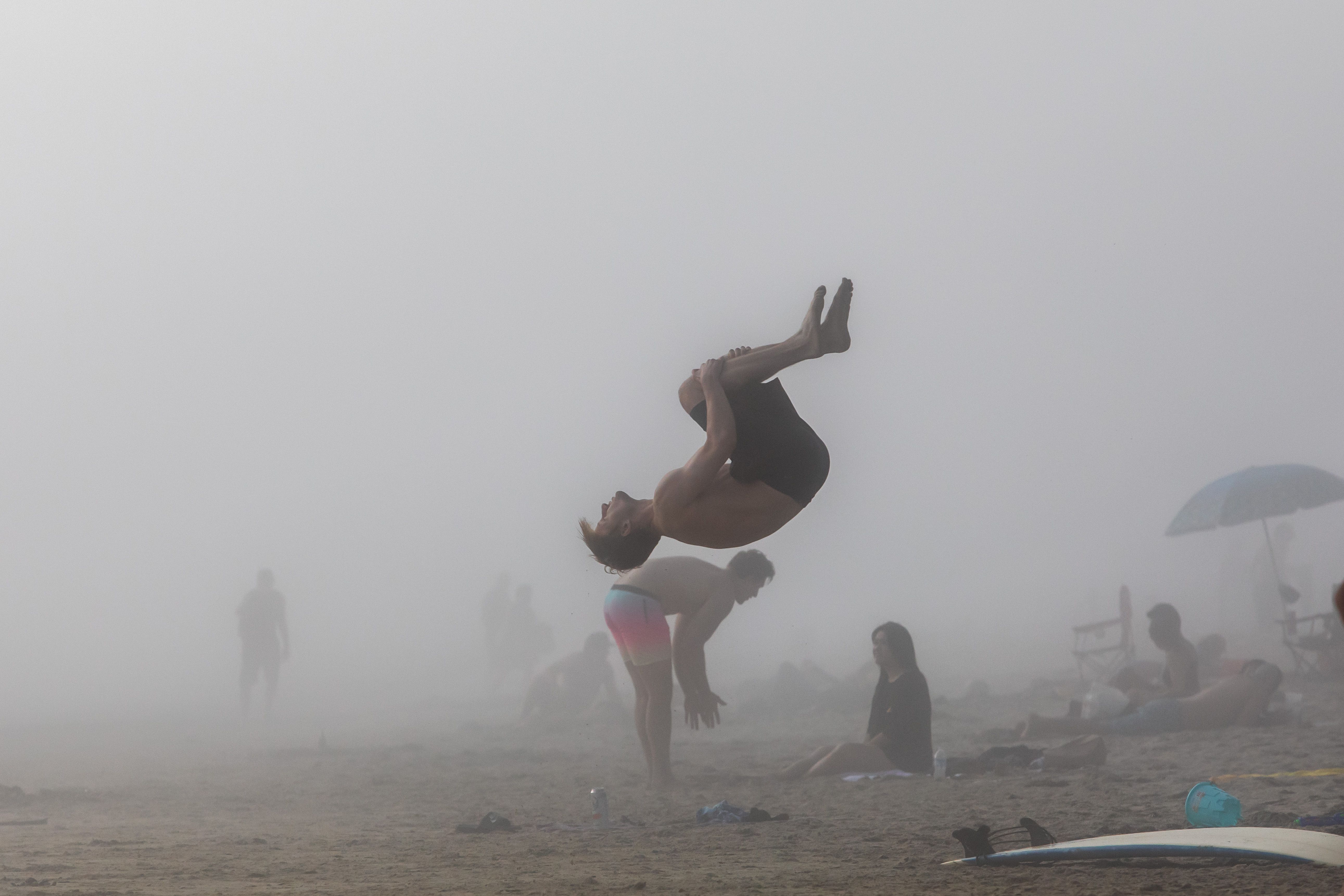 People enjoy the beach through the afternoon fog amid the novel coronavirus pandemic in Huntington Beach, California on April 25, 2020.