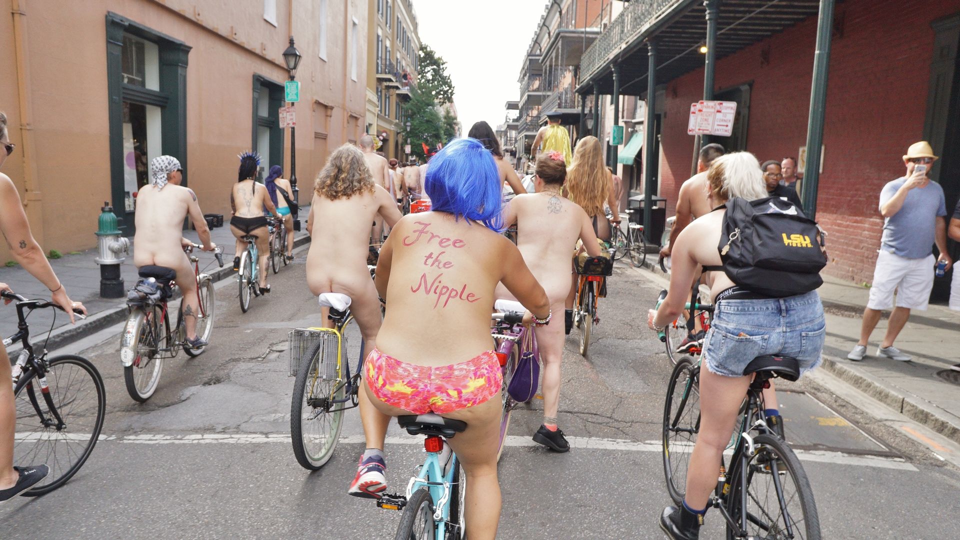 A group of partially-clothed cyclists roll through the French Quarter.