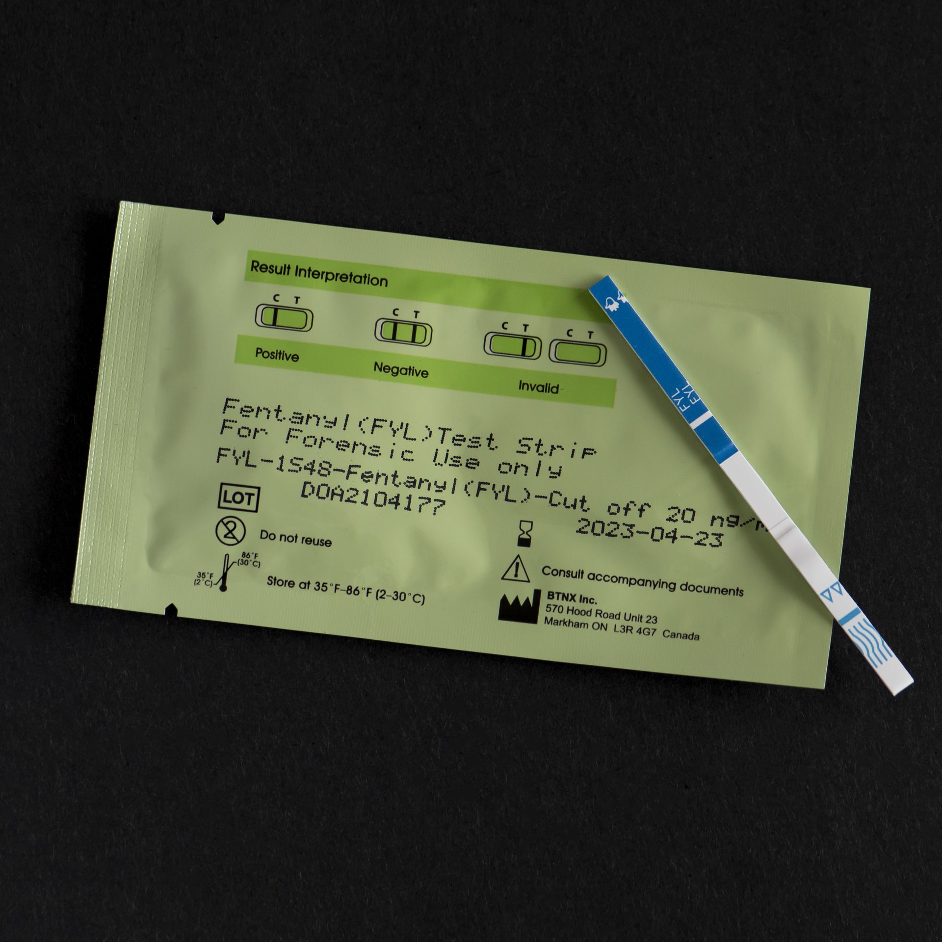 Photo of a fentanyl test strip laying on top of a small yellow packet
