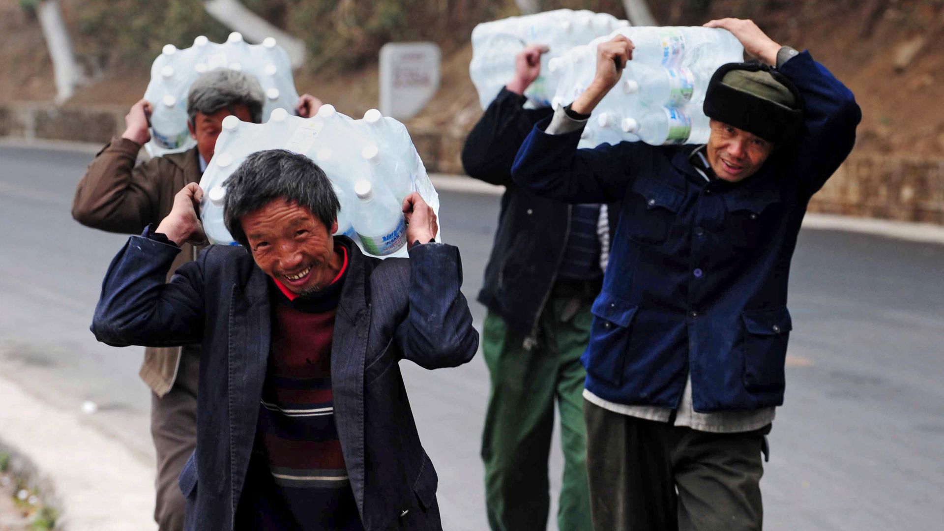 Chinese villagers carrying large gallons of water on their shoulders due to drought