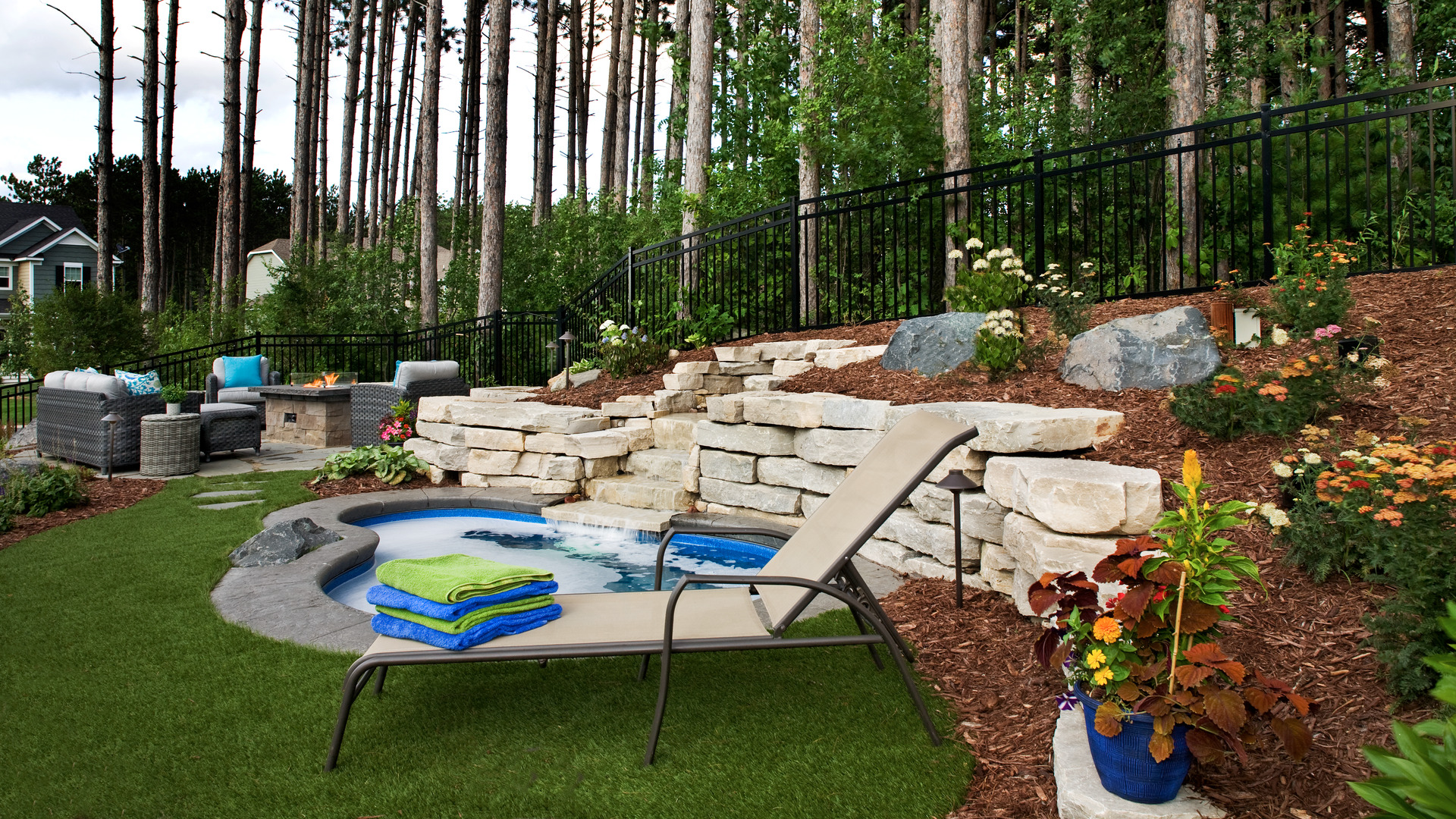 a small pool in a backyard with a fire pit and trees