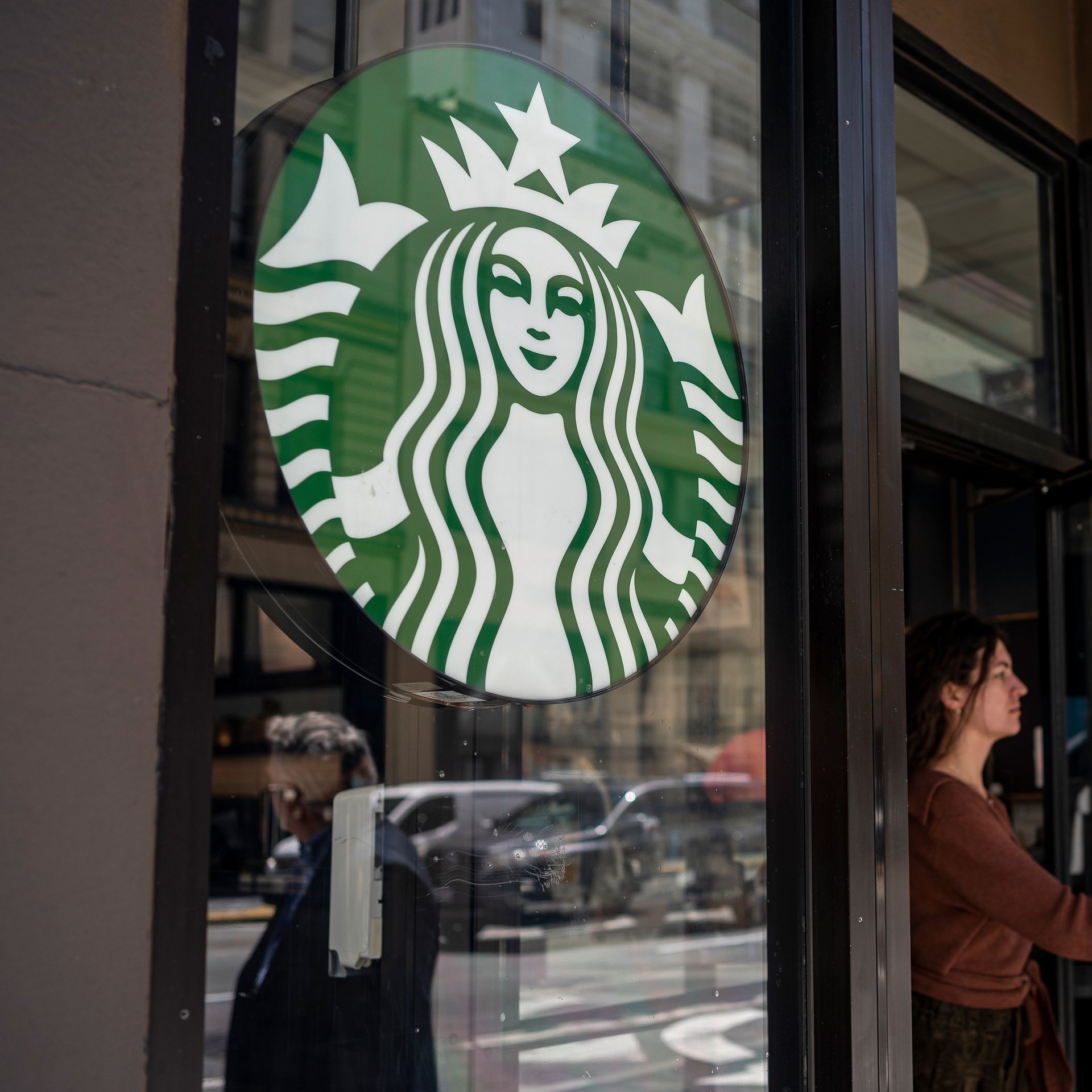 Picture of the Starbucks logo in a location, with a person walking out