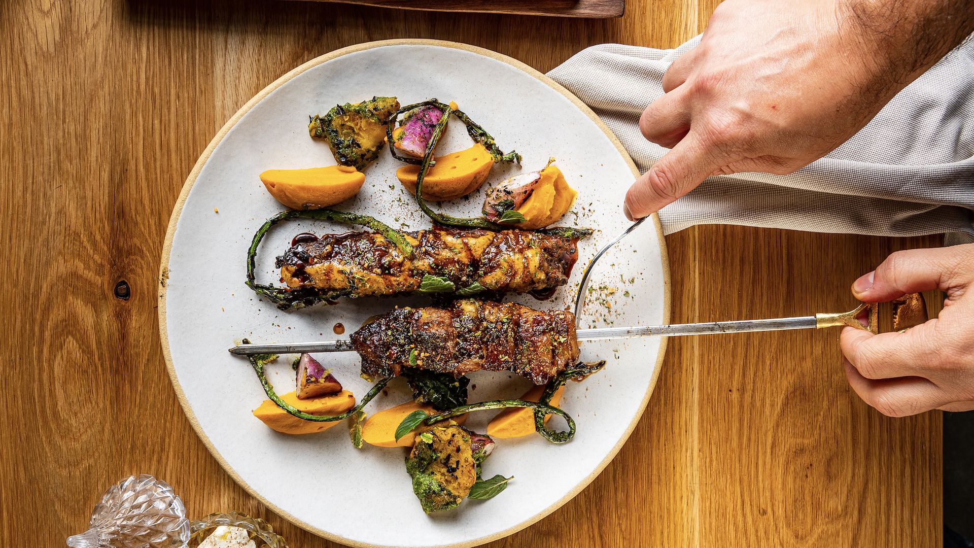 A person cutting food on a plate.