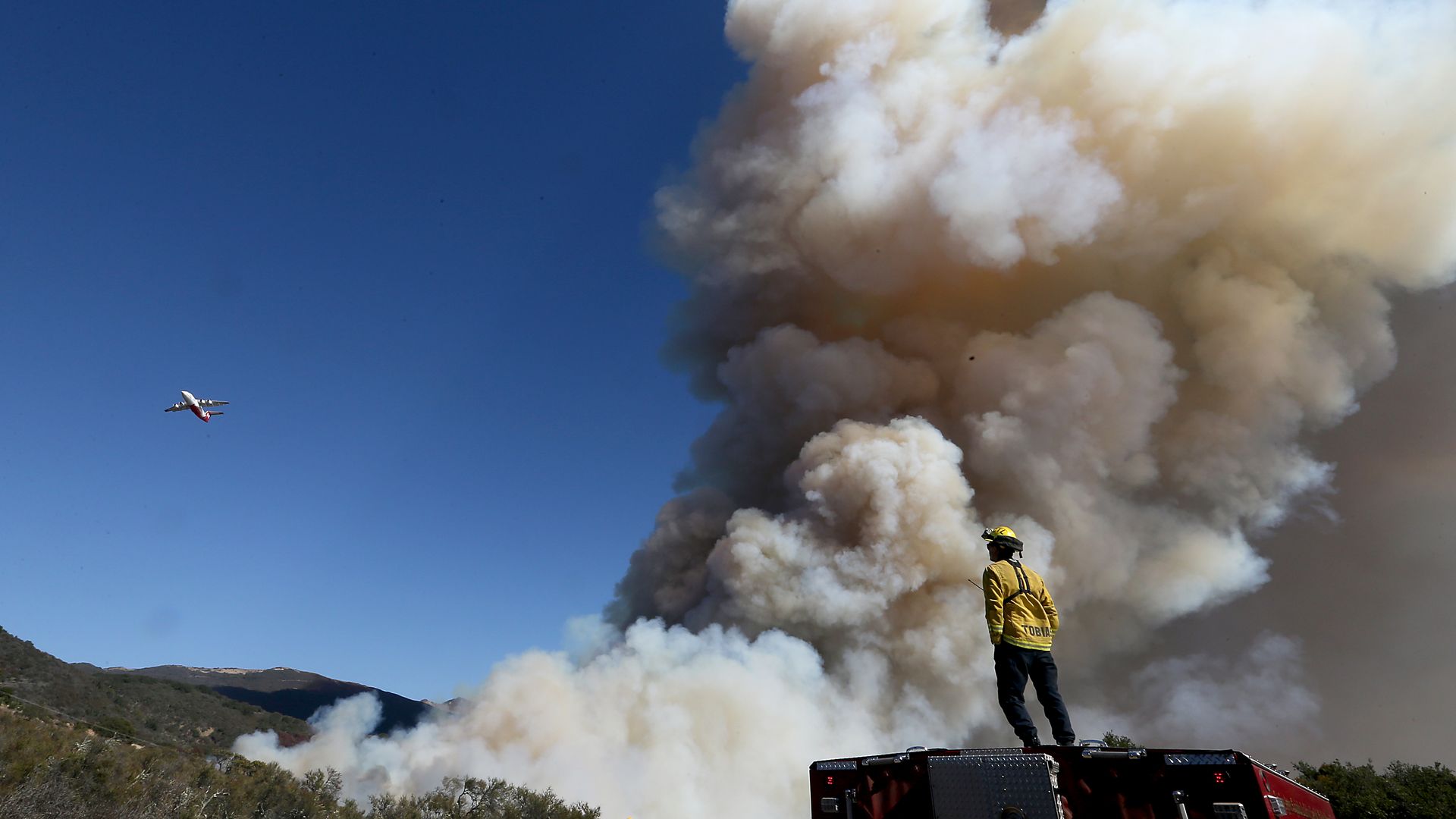 Firefighter stands in front of a California wildfire.