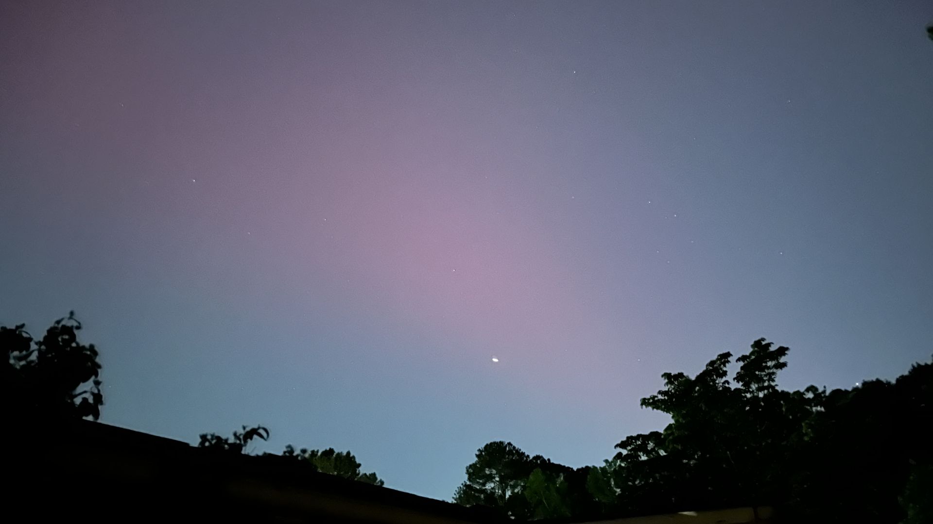 A photo of an evening sky with a faint pink glow during Northern Lights