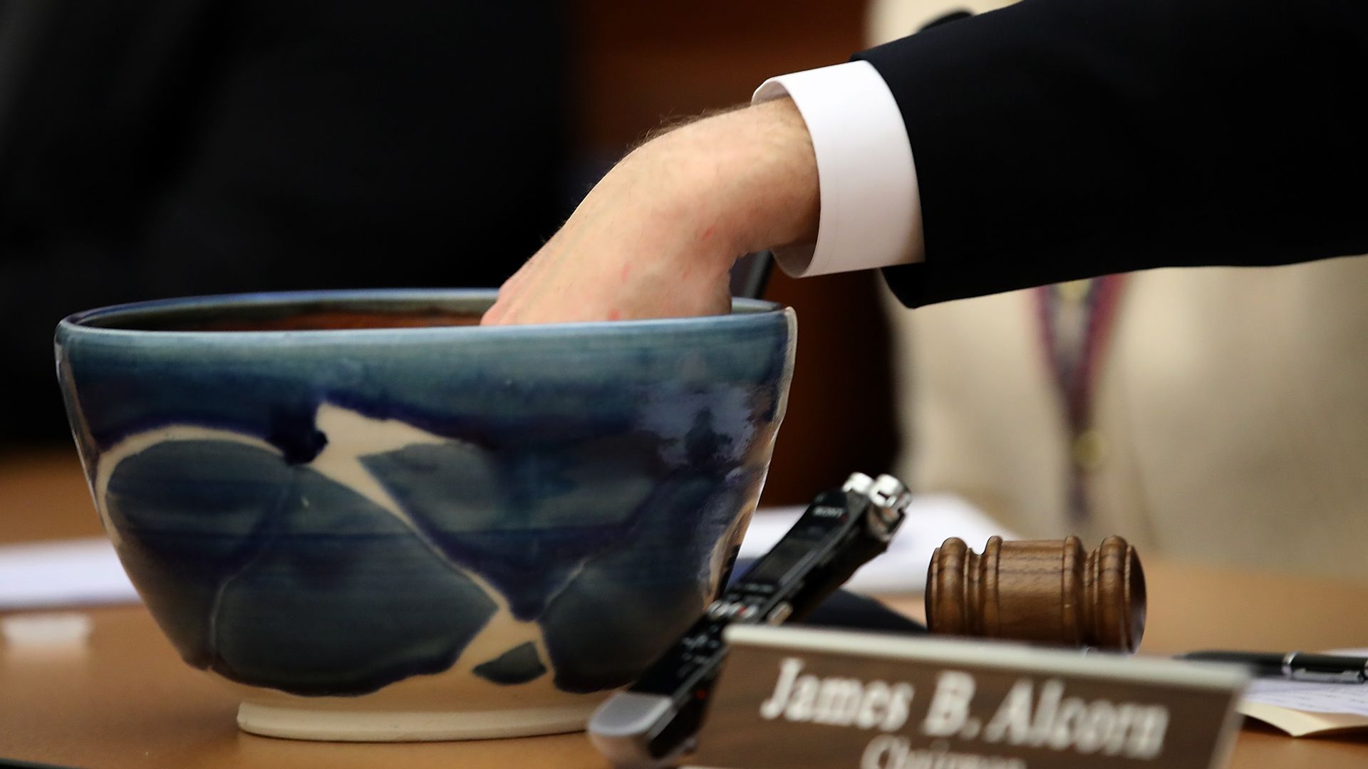 Someone has their hand in a bowl to draw names to settle an election tie