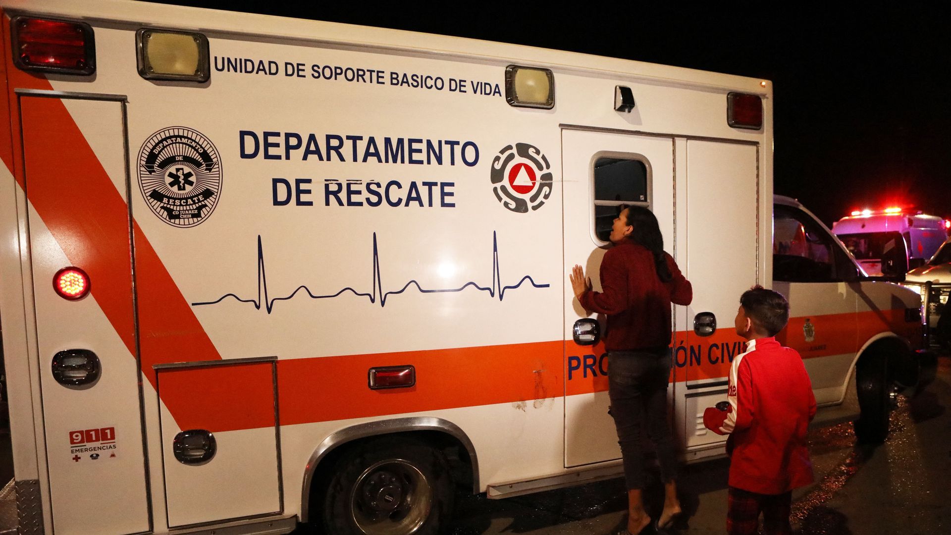 A woman leans against the window of an ambulance trying to get a look at her husband who was injured in a fire in Juarez, Mexico, that killed at least 40 people