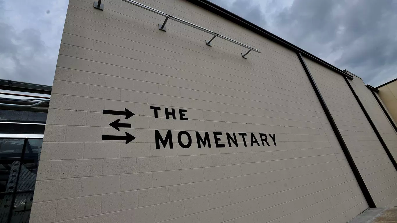 A wall that says the Momentary with a logo