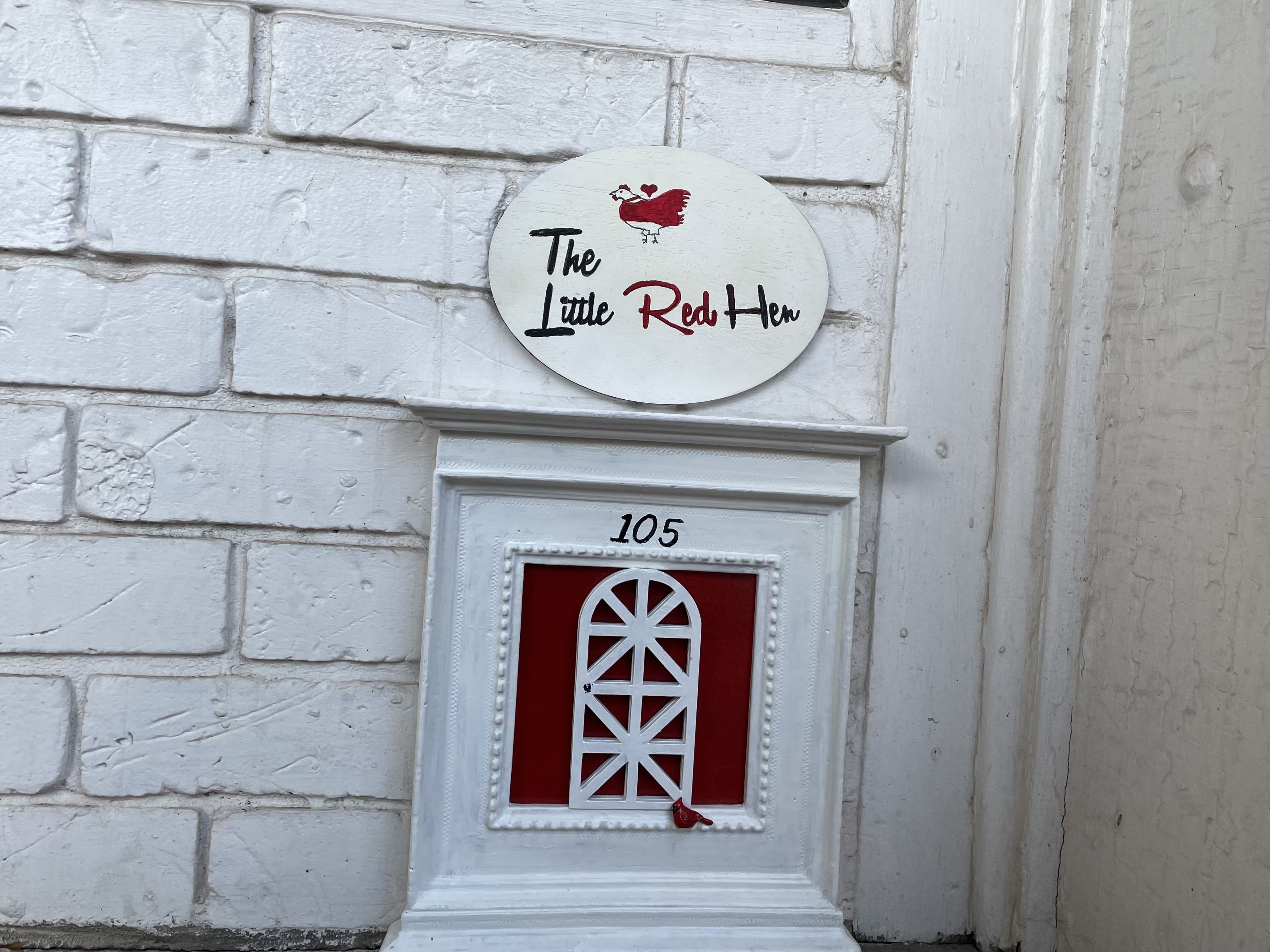 A little red door under a tiny sign that says Little Red Hen