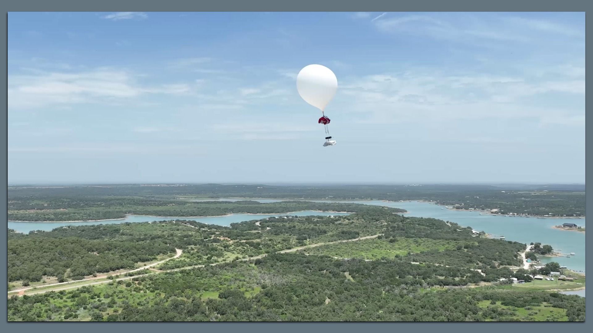 A robot attached to a balloon floating over wetlands.