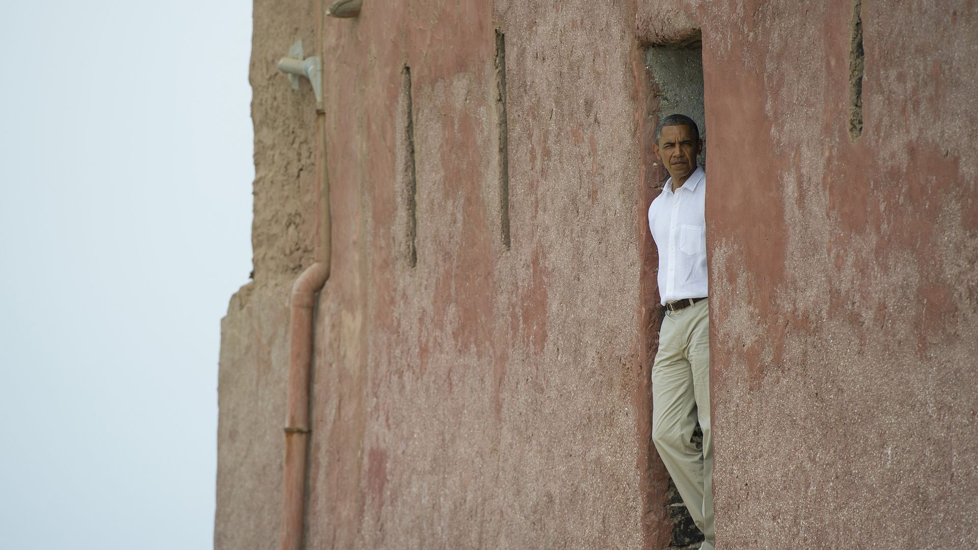 Obama stands in a doorway looking out