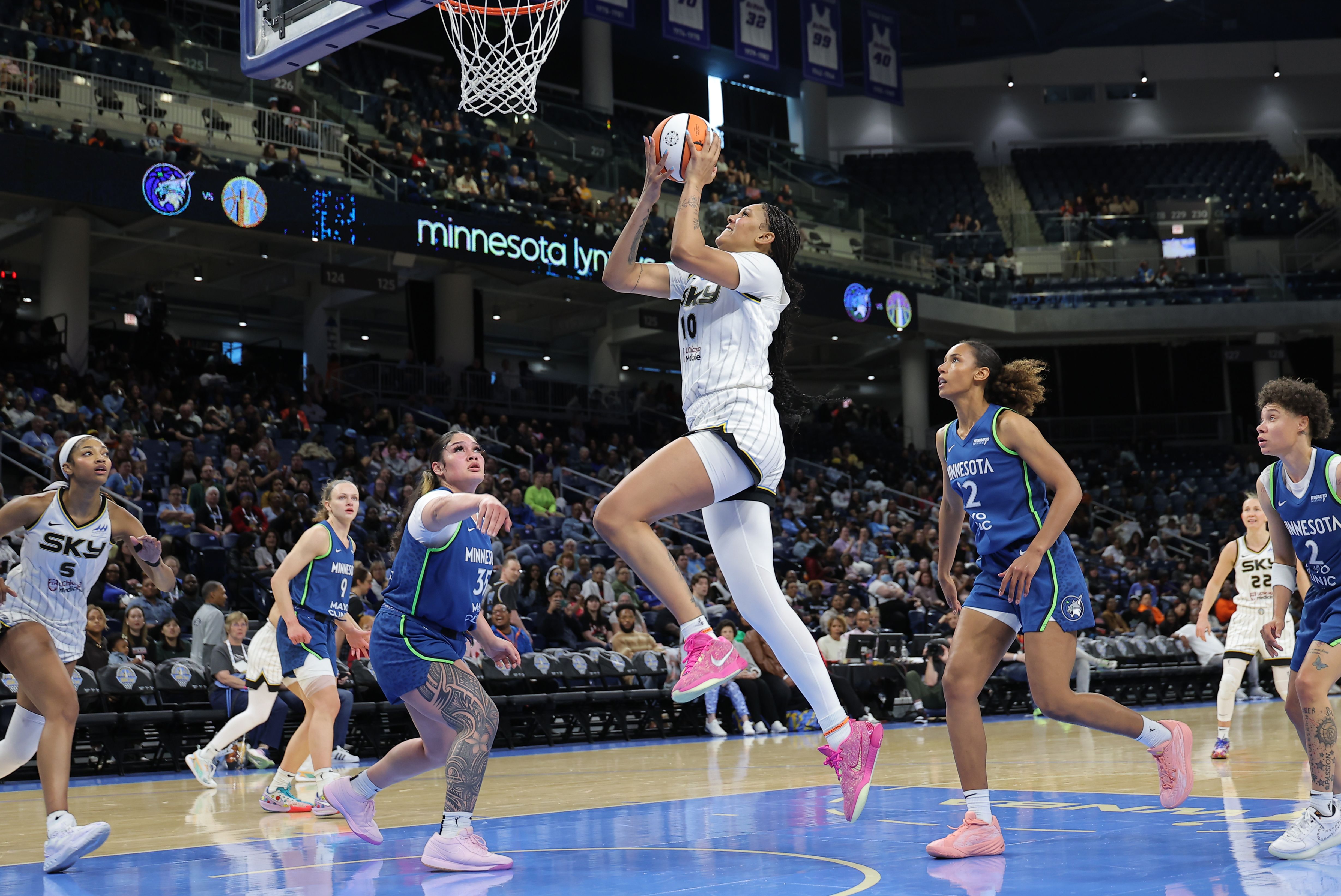 Photo of a woman shooting a basketball during a game on a court. 