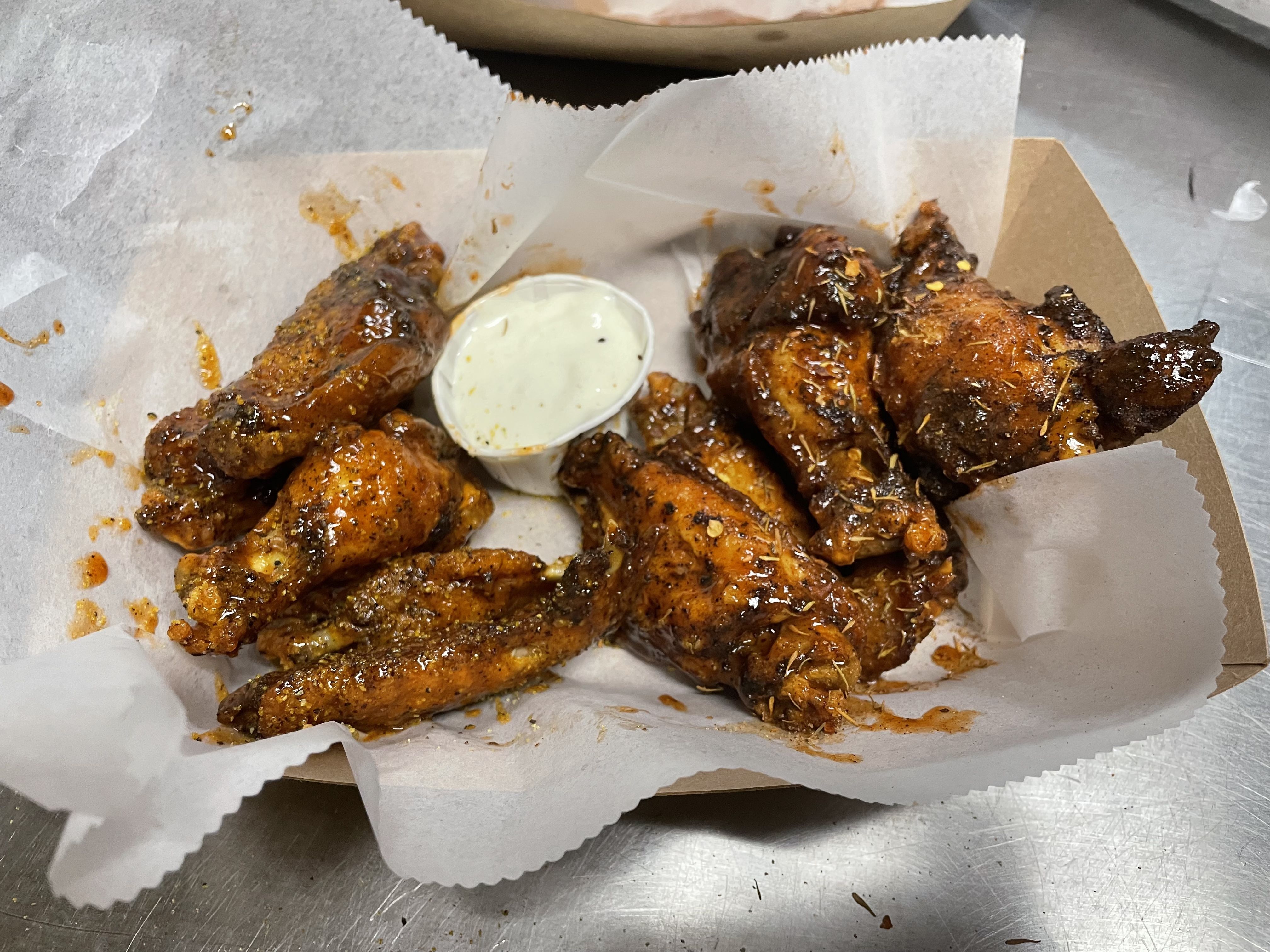 A photo of a basket of smoked wings and ranch or blue cheese