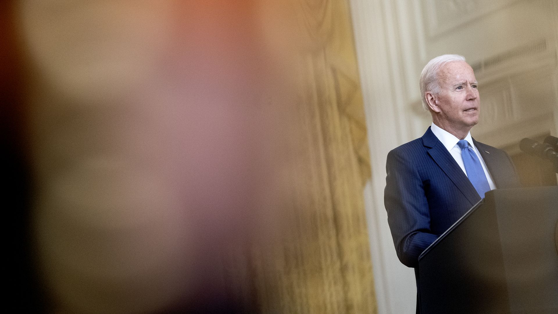 Photo of Joe Biden speaking from a podium in the right half of the photo
