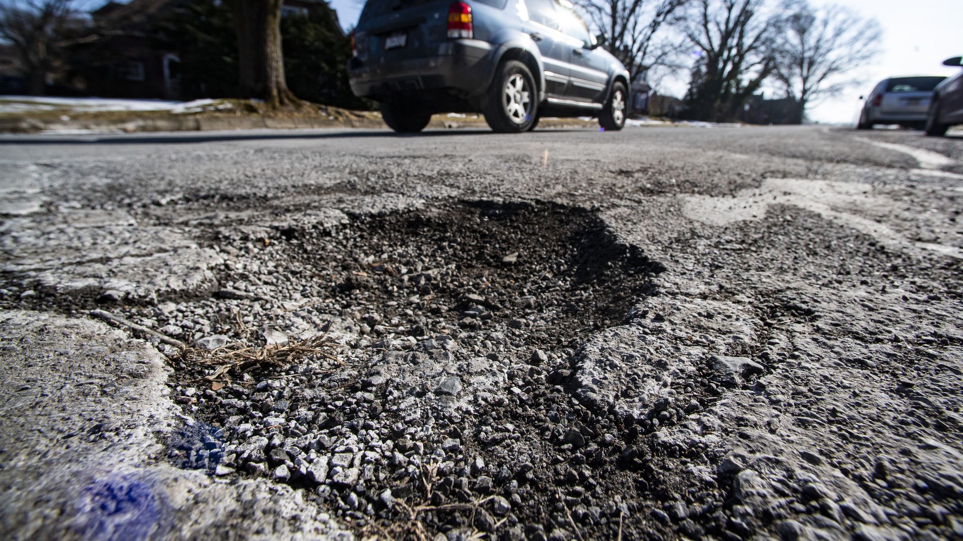 A vehicle dries by a pothole.