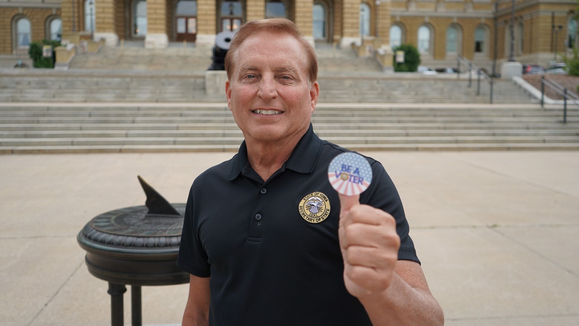 Paul Pate holding up a "Be a Voter" sticker
