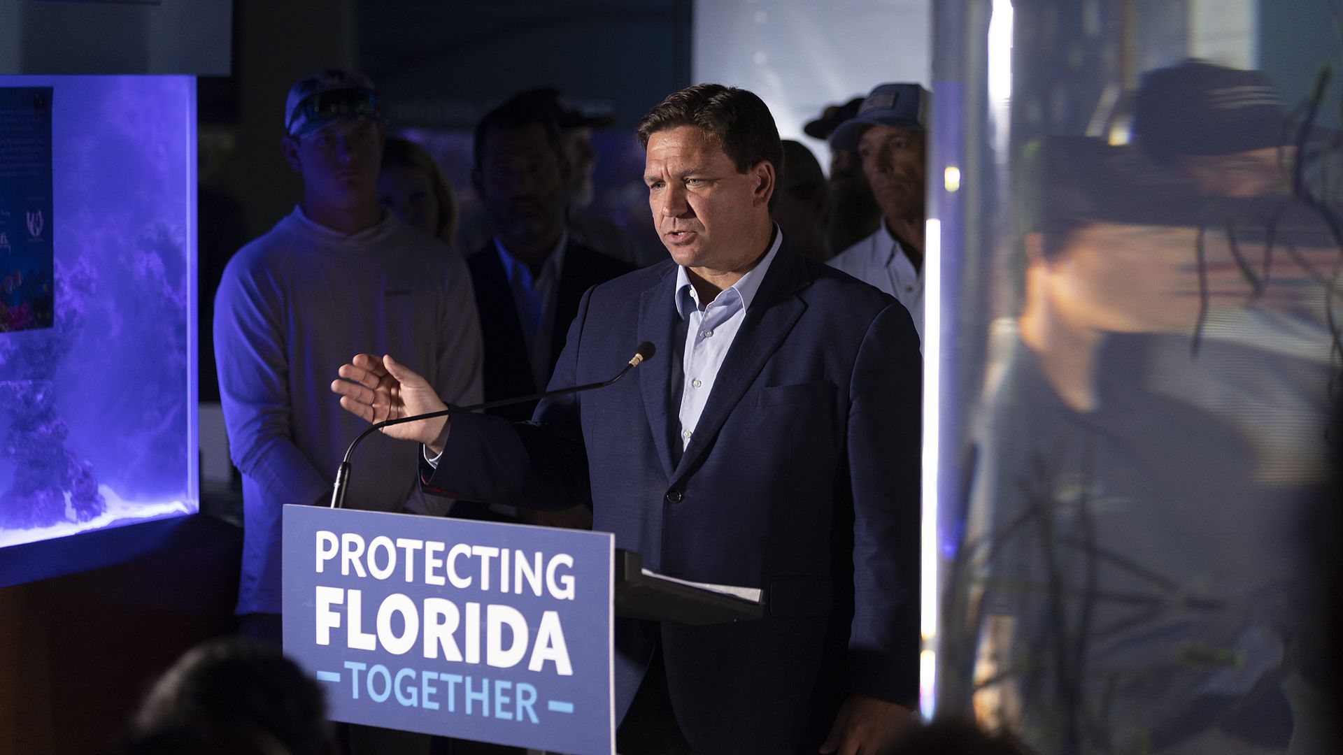 Photo of Ron DeSantis speaking from a podium while waving his right hand