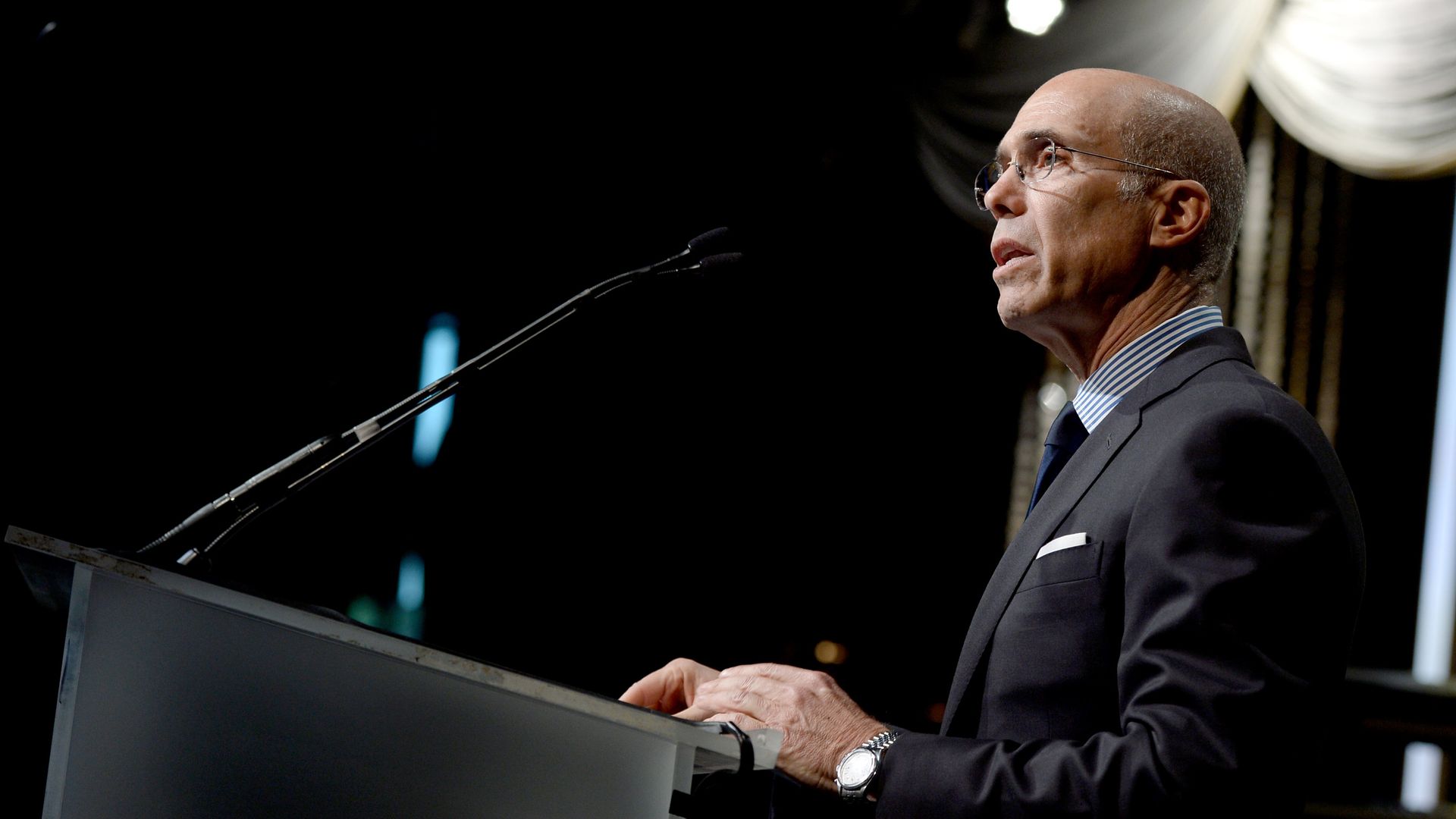 A man stands at a lectern with a microphone in front of him.