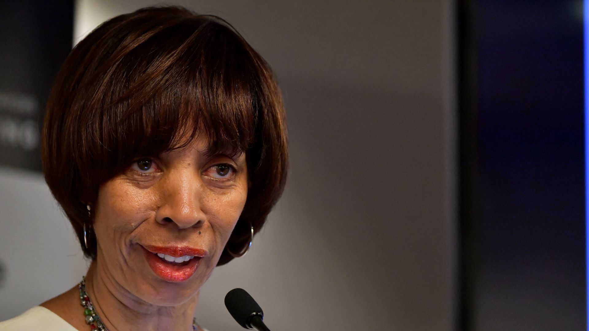 In this image, Catherine Pugh stands and speaks into a microphone. 