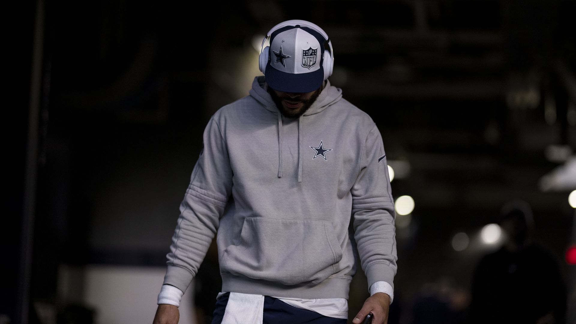 A man wearing a gray hoodie and headphones looks down