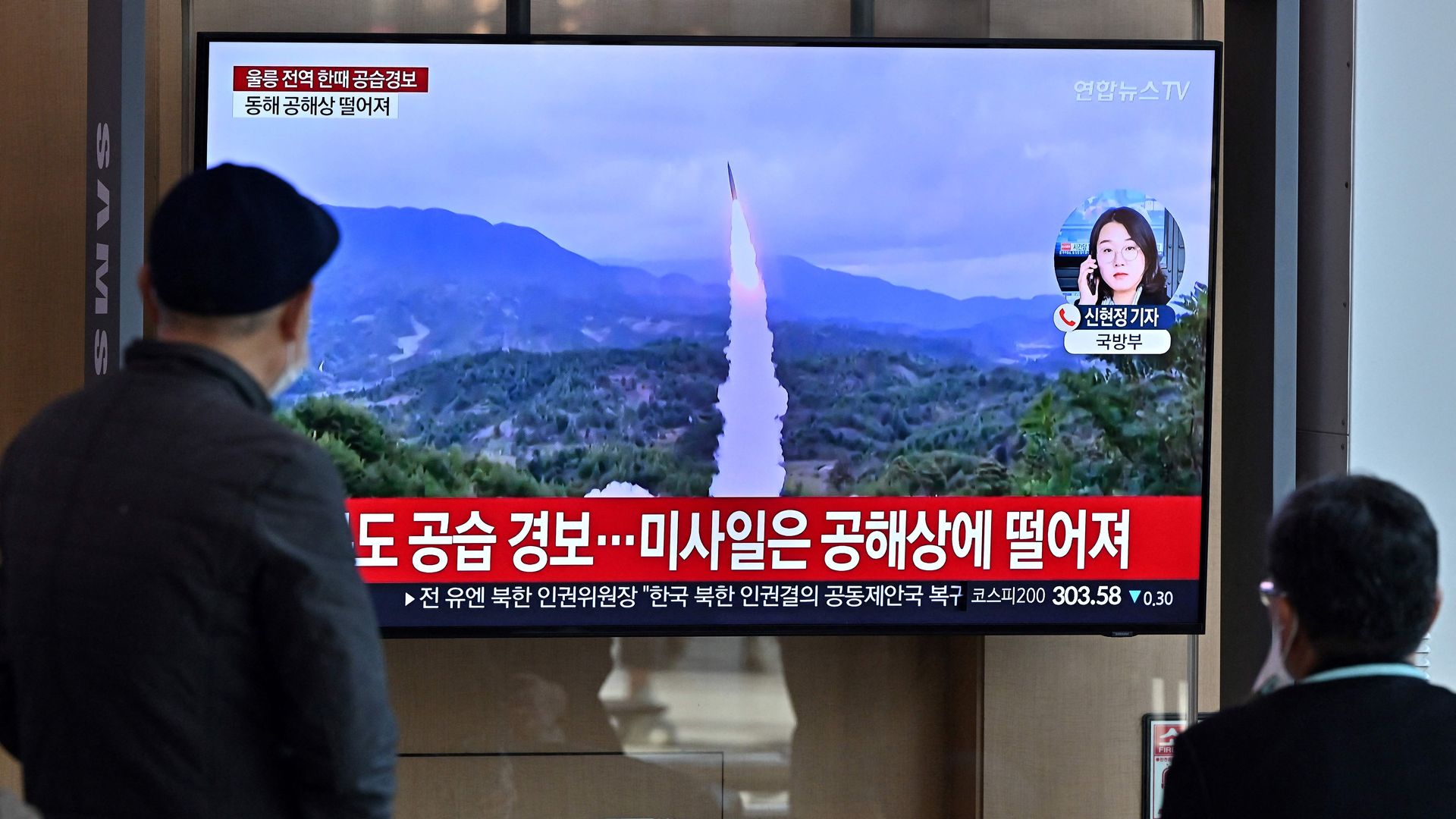 People watch a television screen showing a news broadcast with file footage of a North Korean missile test, at a railway station in Seoul on November 2.