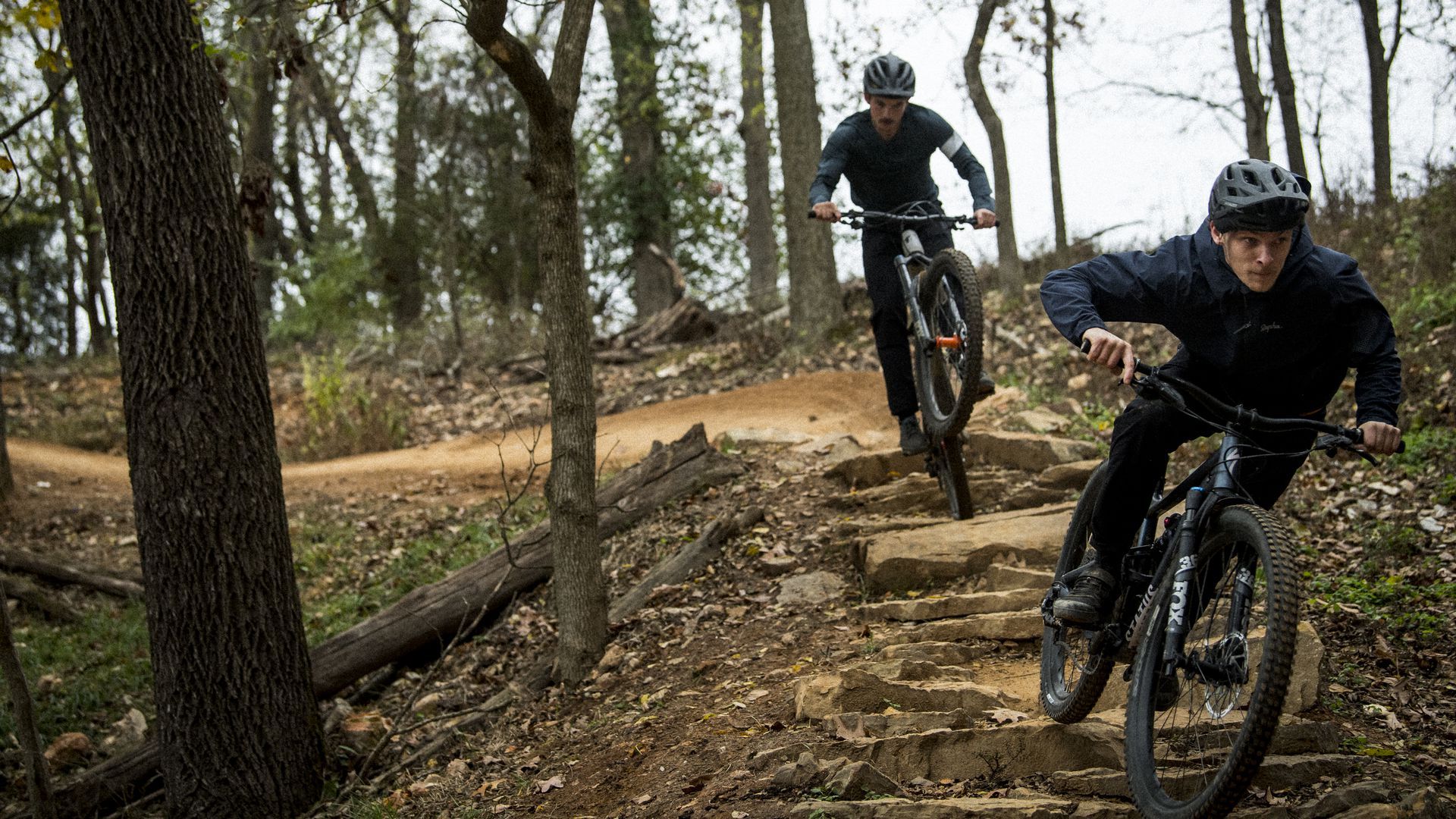 Two cyclists ride bikes on a dirt path
