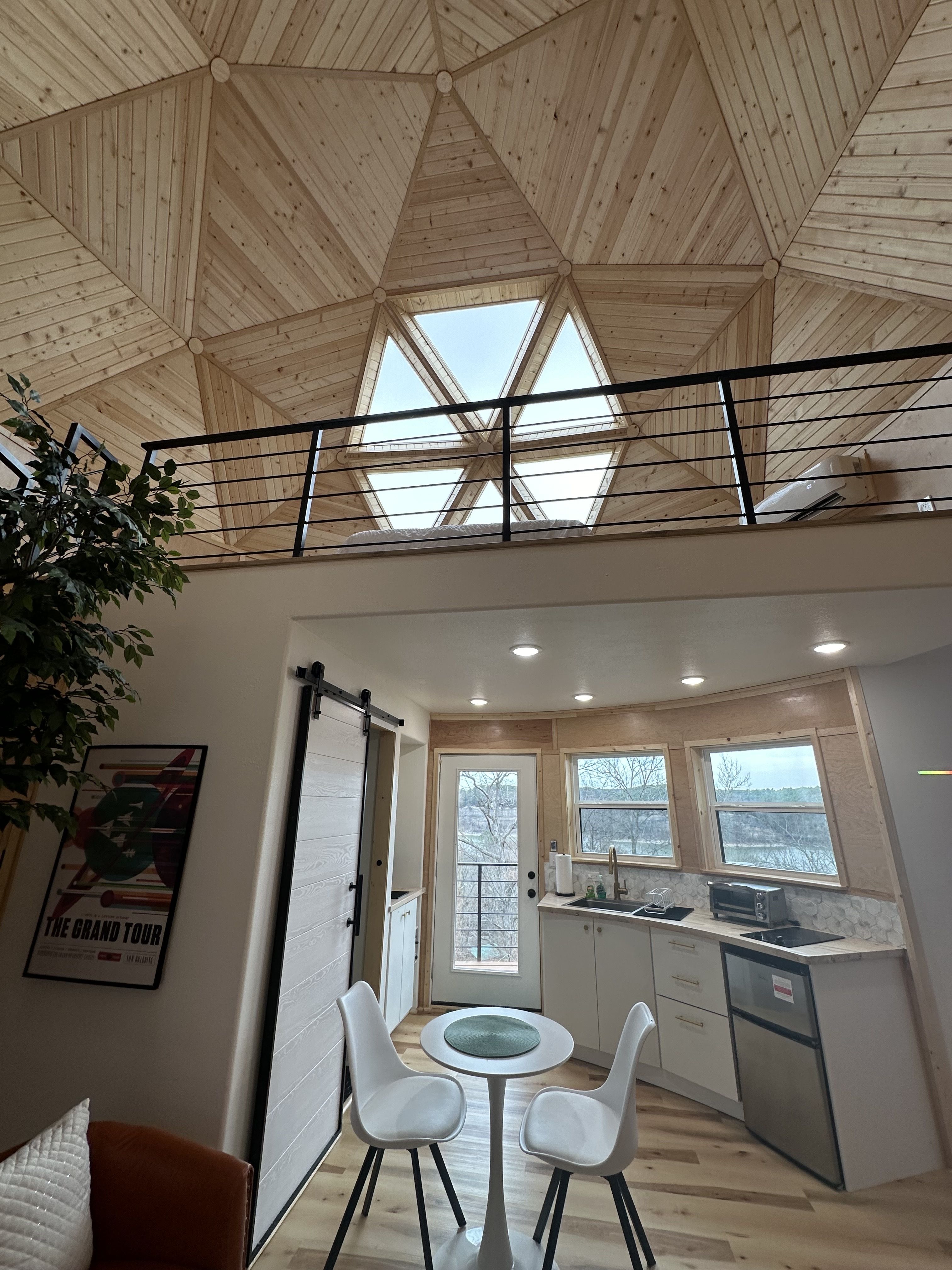 A photo of a small kitchenette and dining room under a dome made of wood and windows.